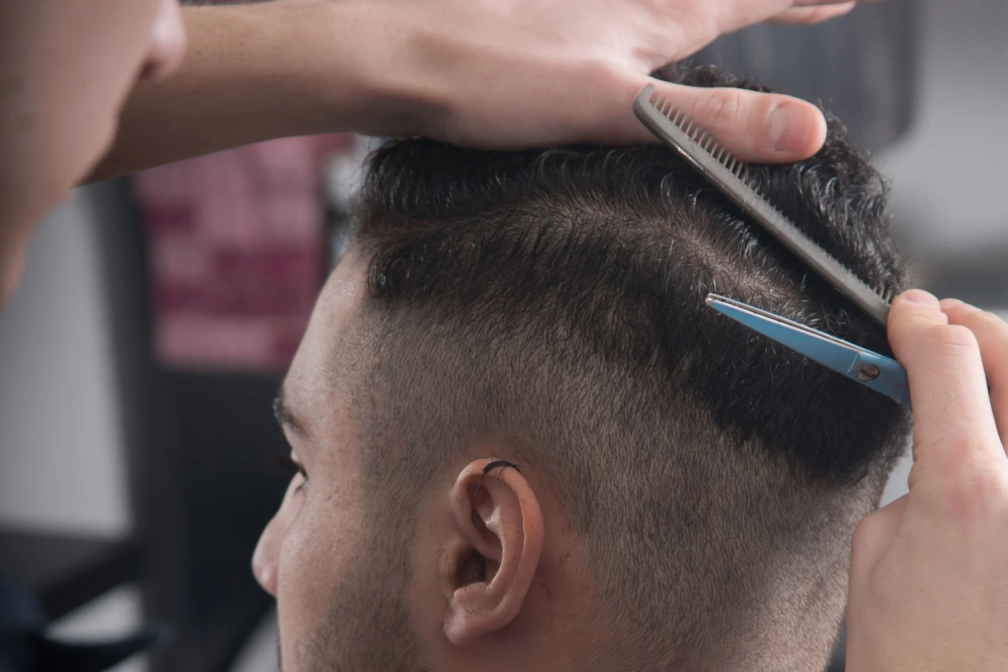 Stylist precision cutting a men's haircut with scissors and comb at Willow's Cove Salon in Mineola, NY