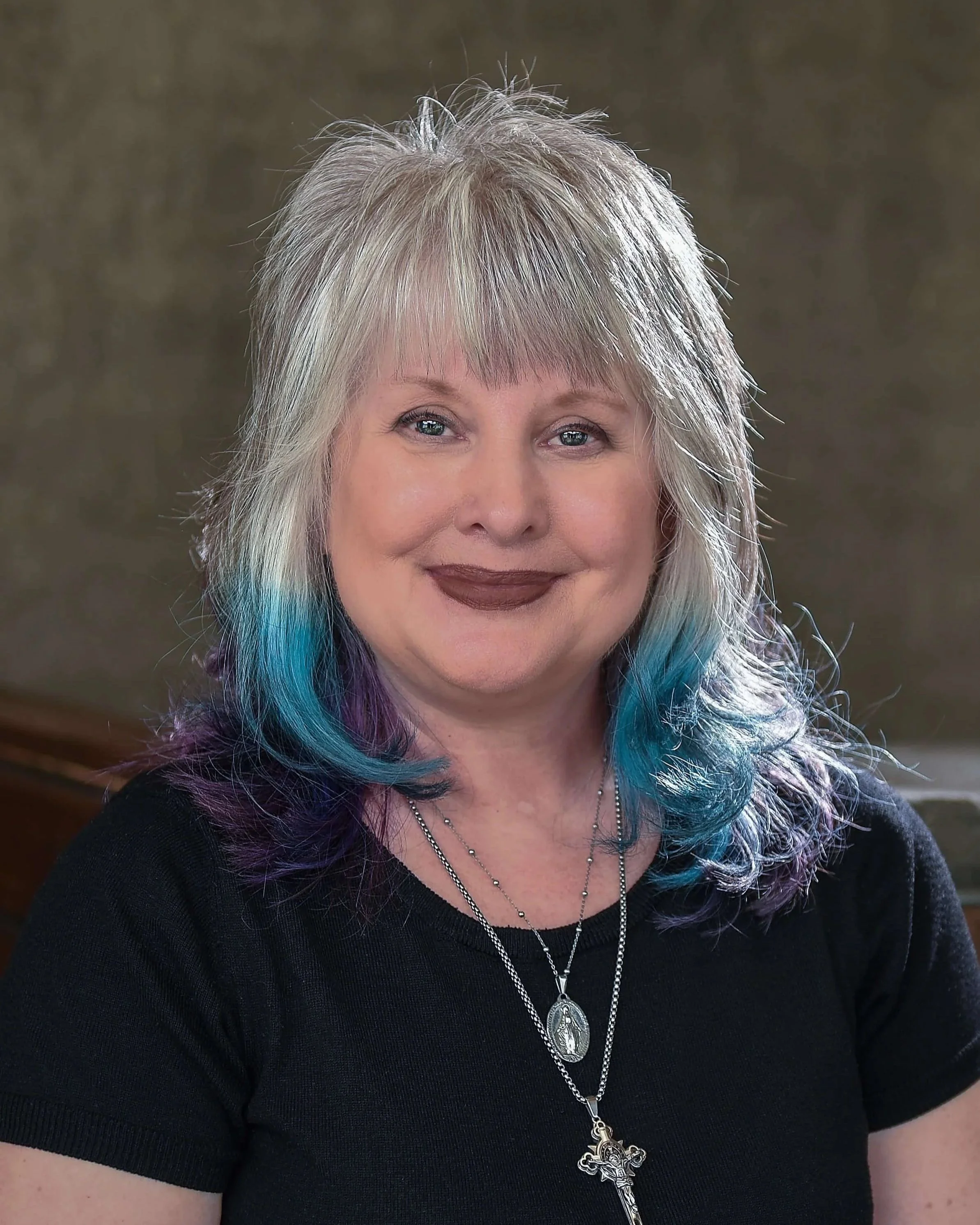 Cathy, stylist at Willow's Cove Salon, smiling with silver and fantasy blue and purple colored hair