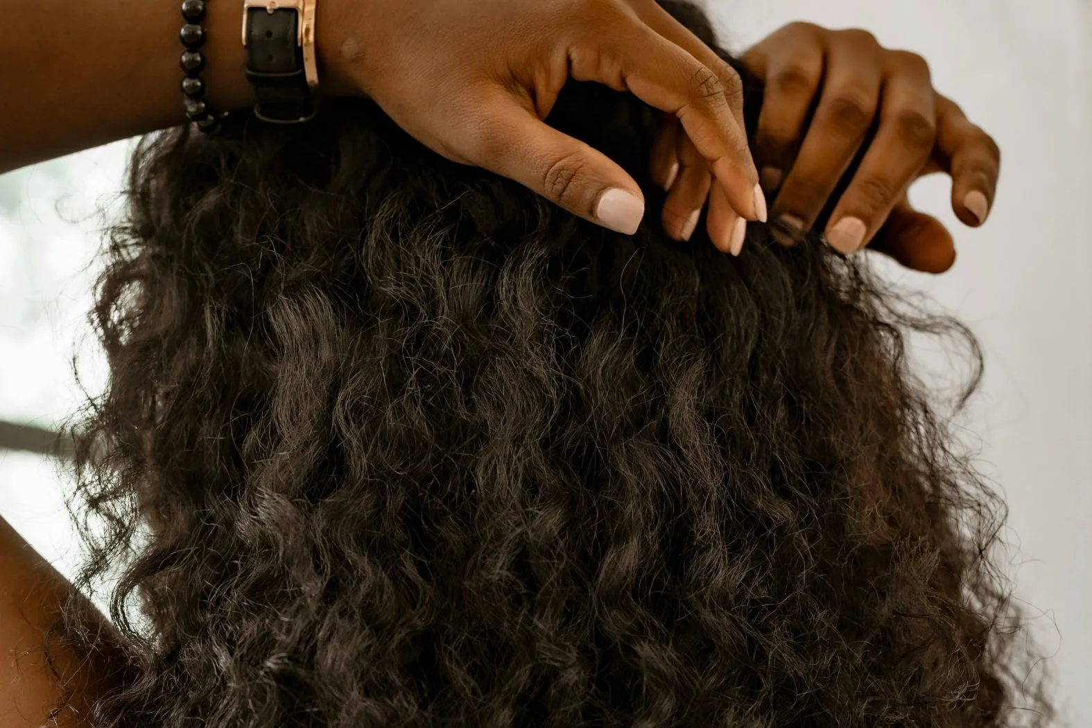 Stylist working through a client's natural curly hair for a weave installation at Willow's Cove Salon in Mineola, NY