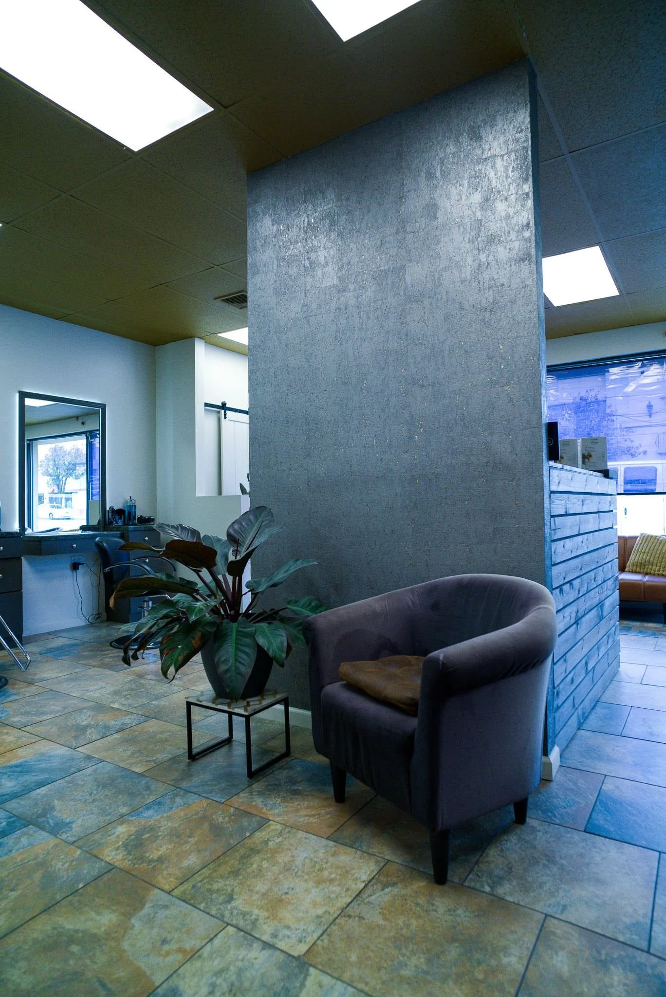 Stylist color matching hair extensions against a client's long blonde hair for extension removal service at Willow's Cove Salon in Mineola, NY