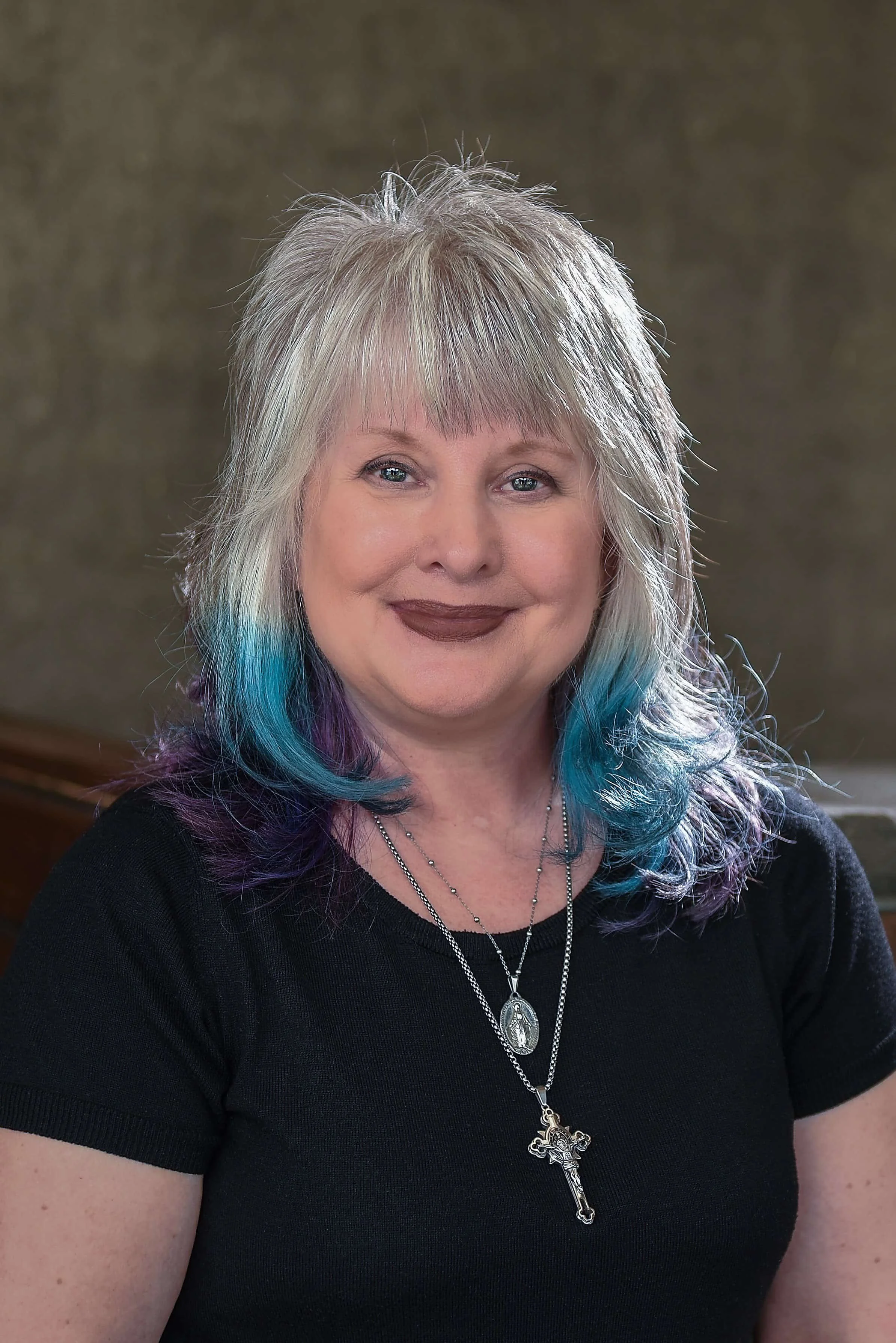 Cathy, stylist at Willow's Cove Salon, smiling with silver and fantasy blue and purple colored hair