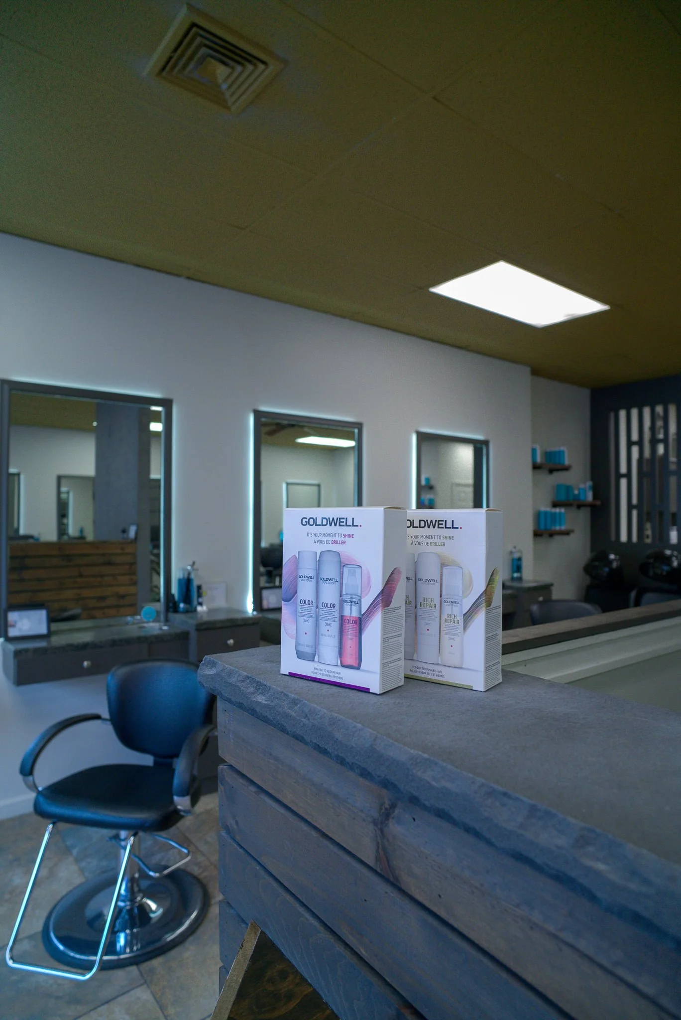Goldwell hair care products displayed on the reception desk at Willow's Cove Salon in Mineola, NY with styling stations in the background