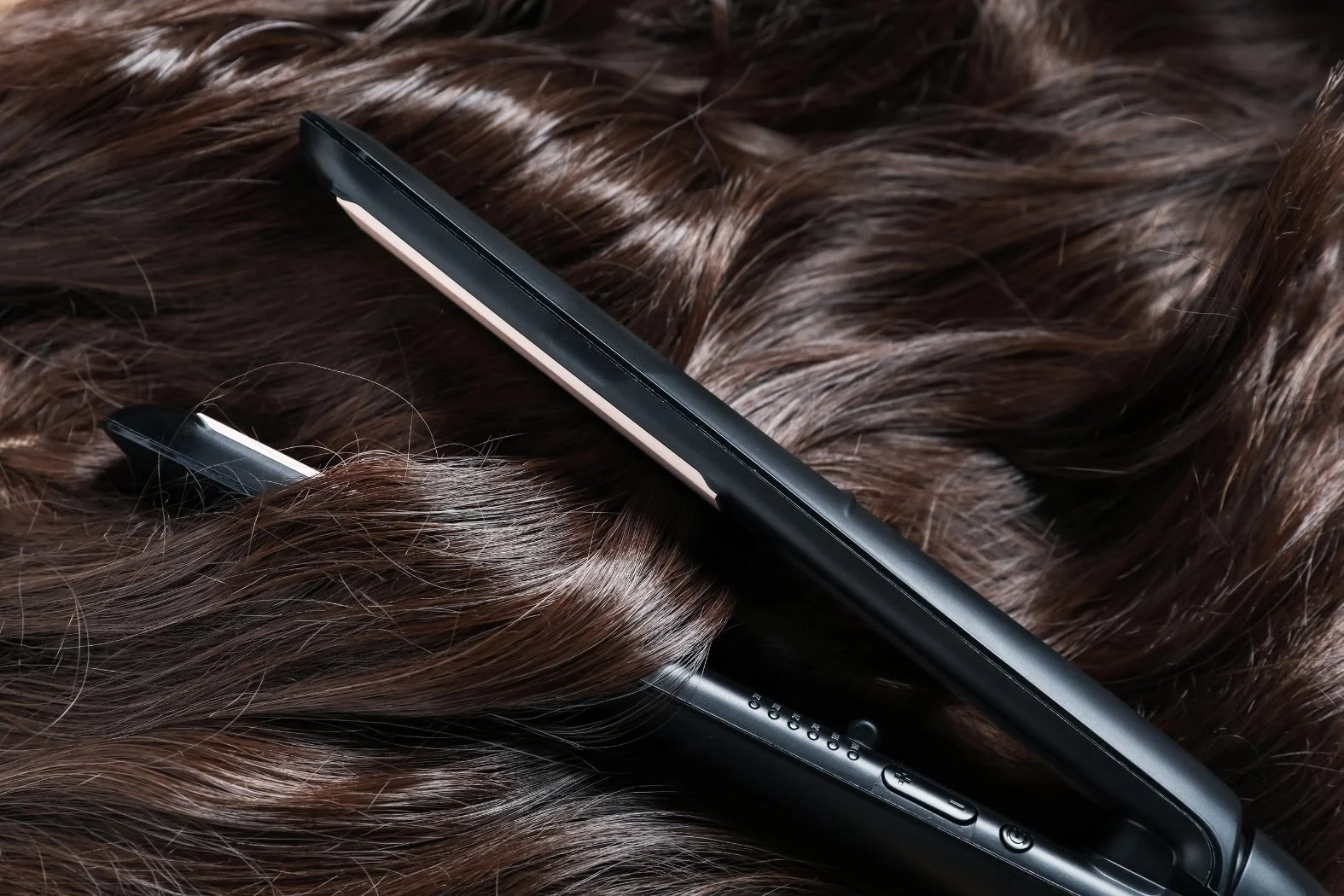 Flat iron resting on smooth, shiny hair after a keratin smoothing treatment at Willow's Cove Salon