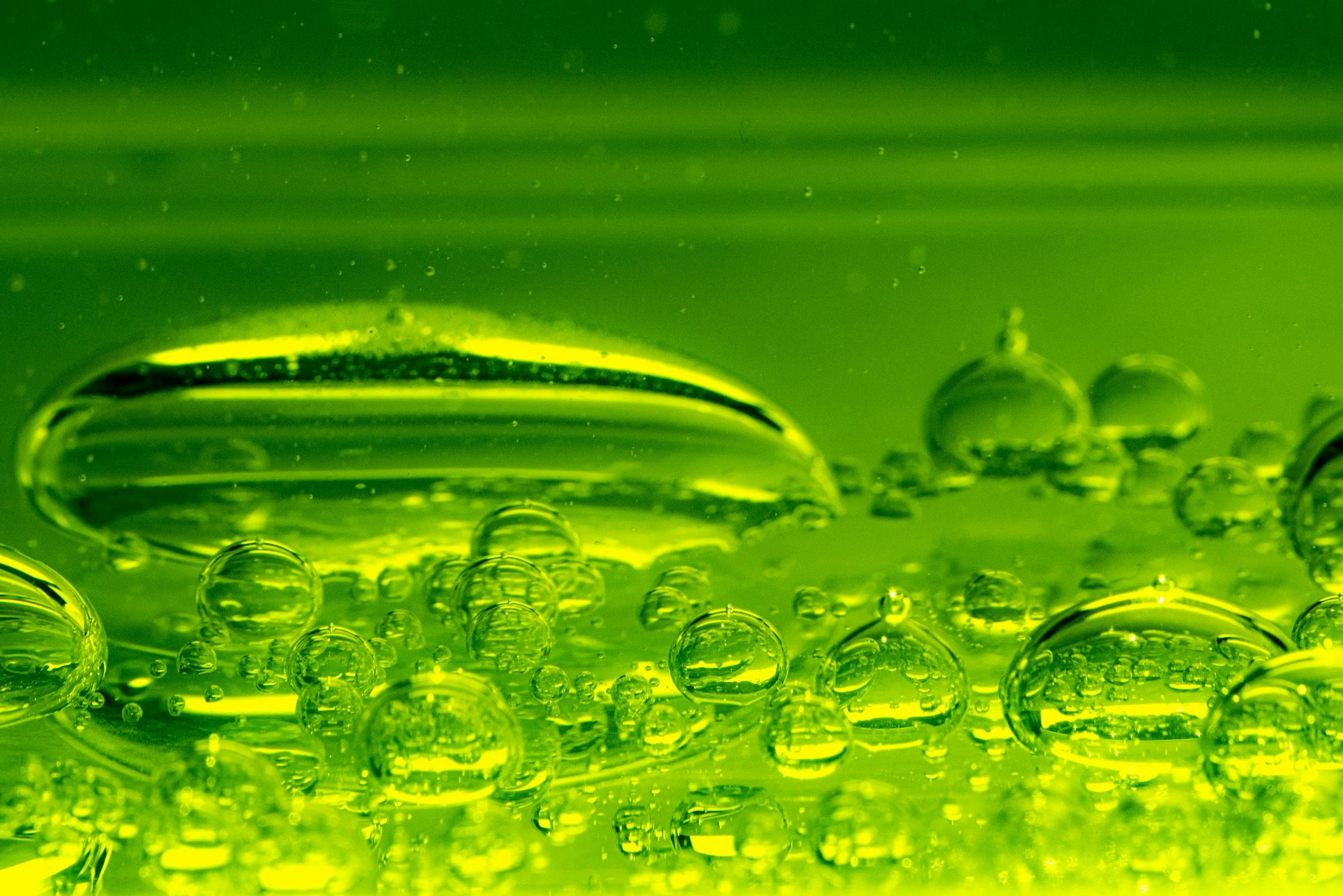 Close-up of green toxic liquid with numerous bubbles of various sizes, some large and others tiny, creating a textured appearance.