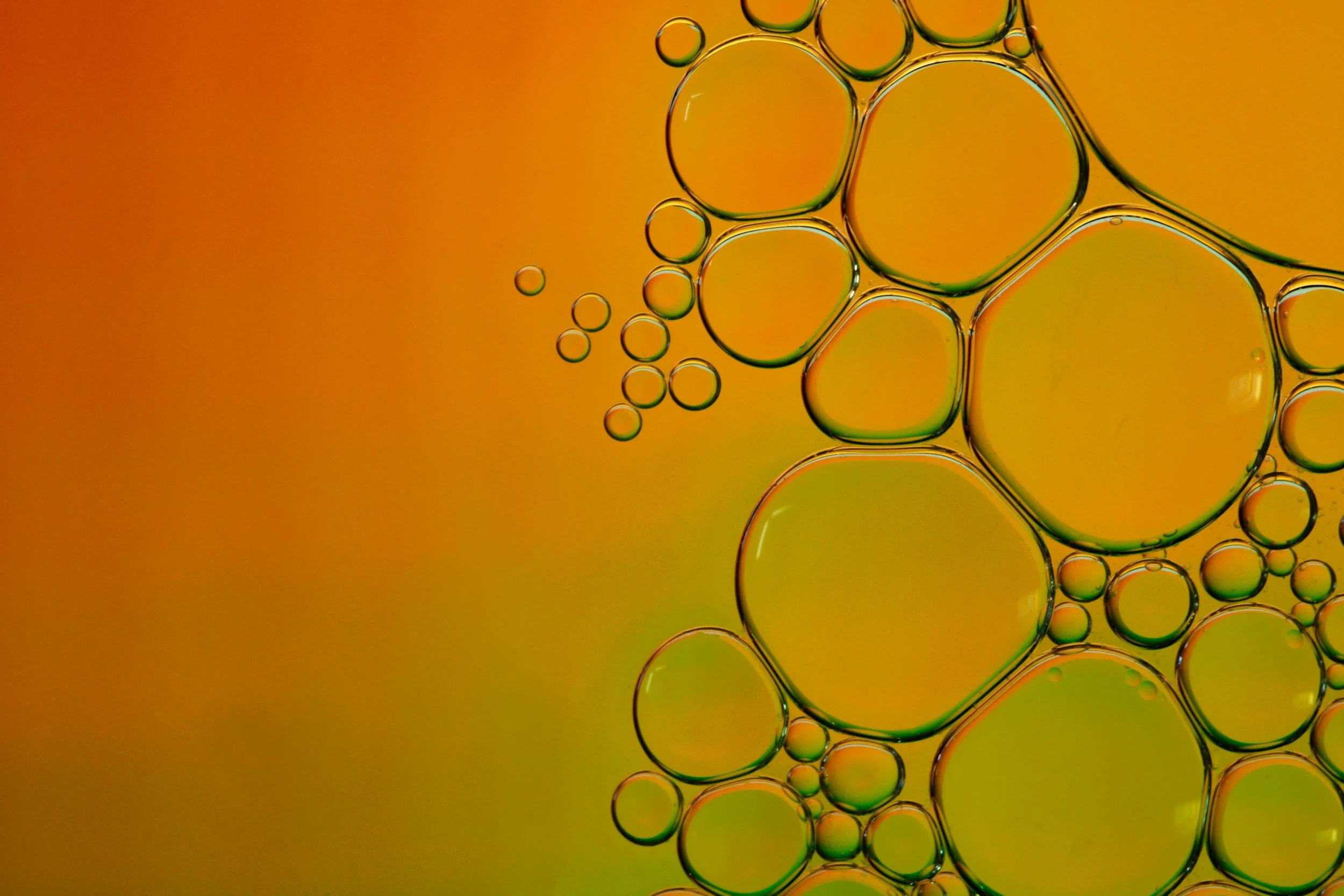 Close-up of oil and water bubbles forming a pattern against an orange background representing the chemical industry.