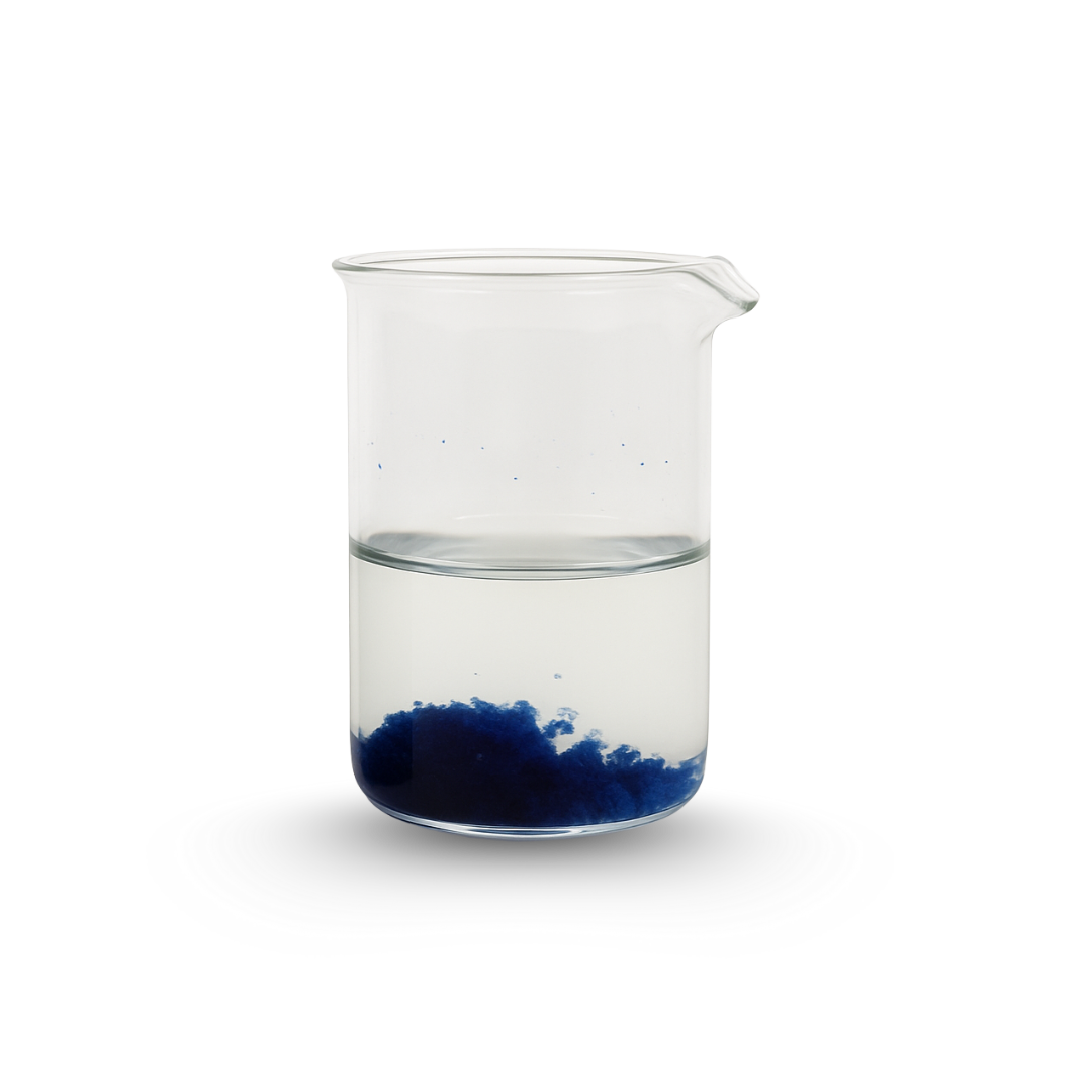 A clear glass beaker filled halfway with water, with dark blue powder settled at the bottom.