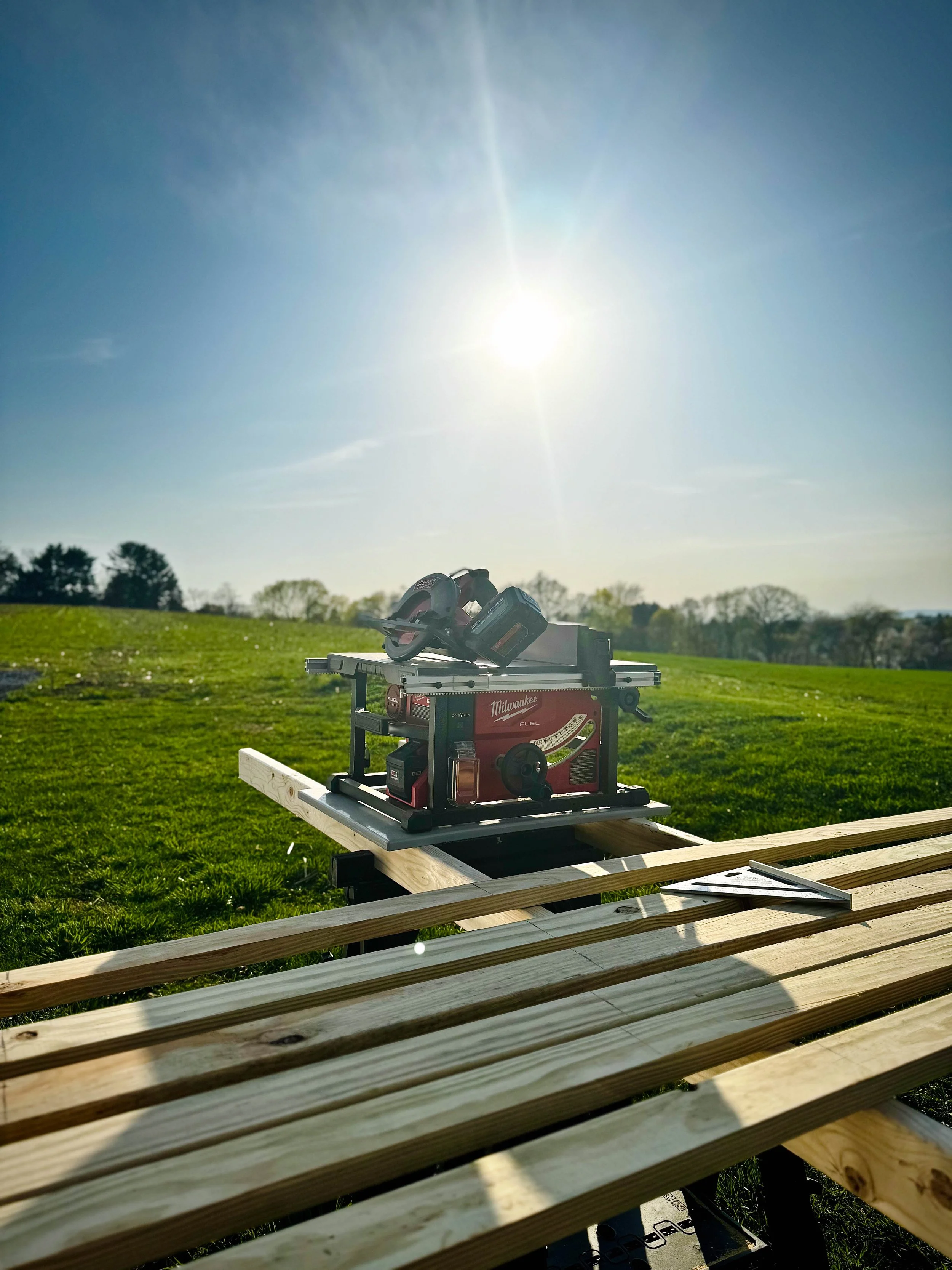 Power tool on a workbench outdoors on a sunny day with a grassy field in the background.