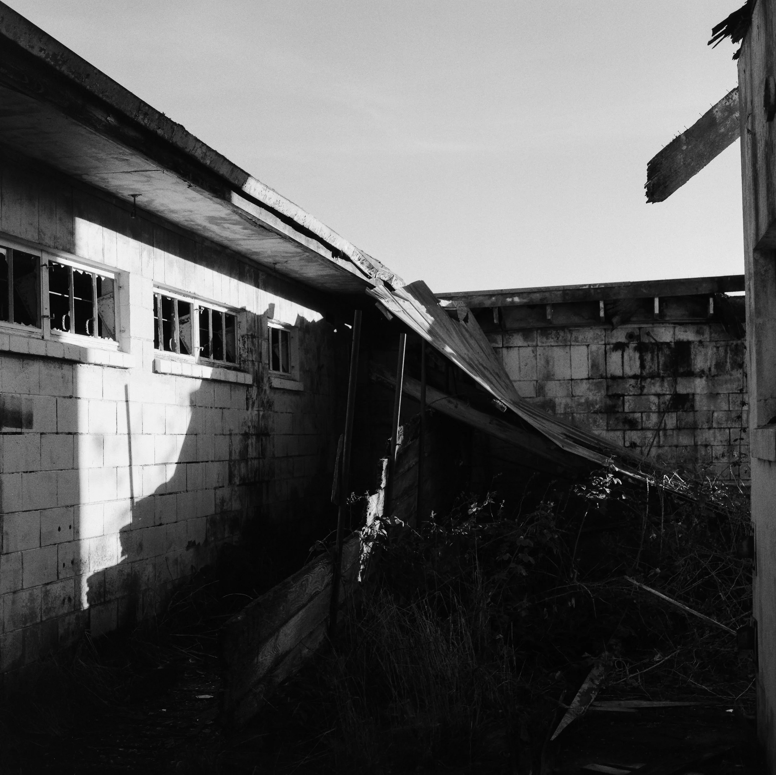 Black and white photo of a dilapidated building with broken windows and a collapsed roof.