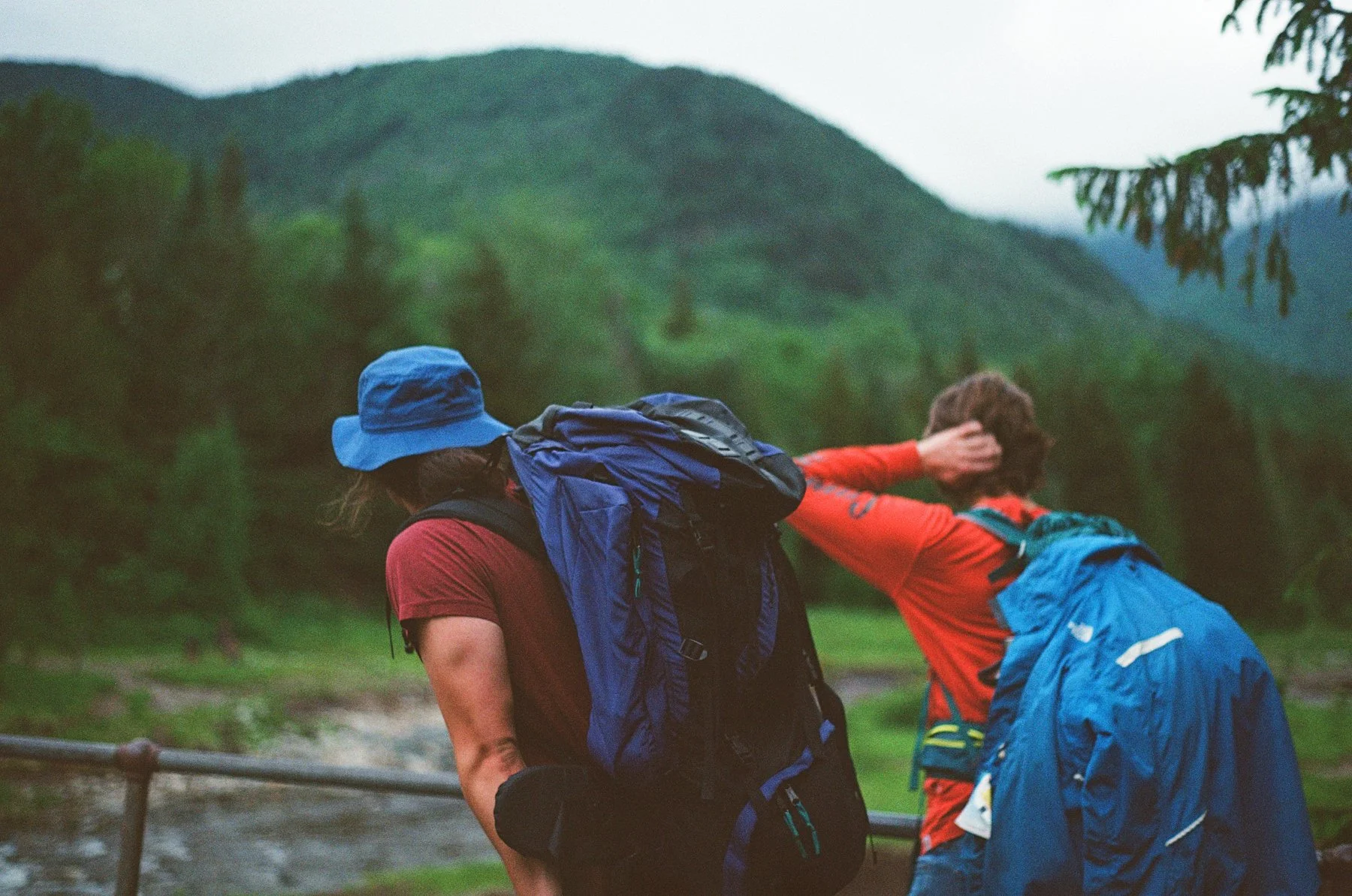 Hikers with backpacks in a green, mountainous outdoor setting.