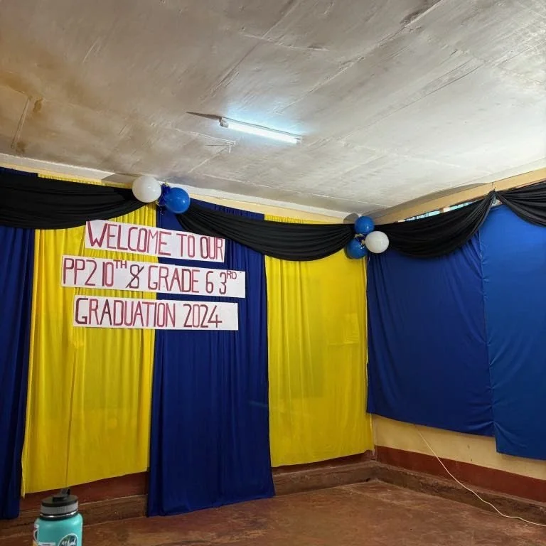 Decorated stage with yellow and blue curtains, black drapes, white and blue balloons, and a sign that reads 'Welcome to our PP 2 10th Grade 6 3rd Graduation 2024'.