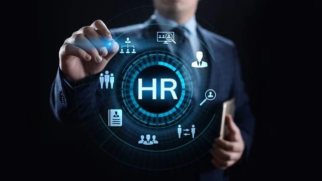 A business person in a suit holding a smartphone interacts with a digital HR interface showing icons related to human resources management.