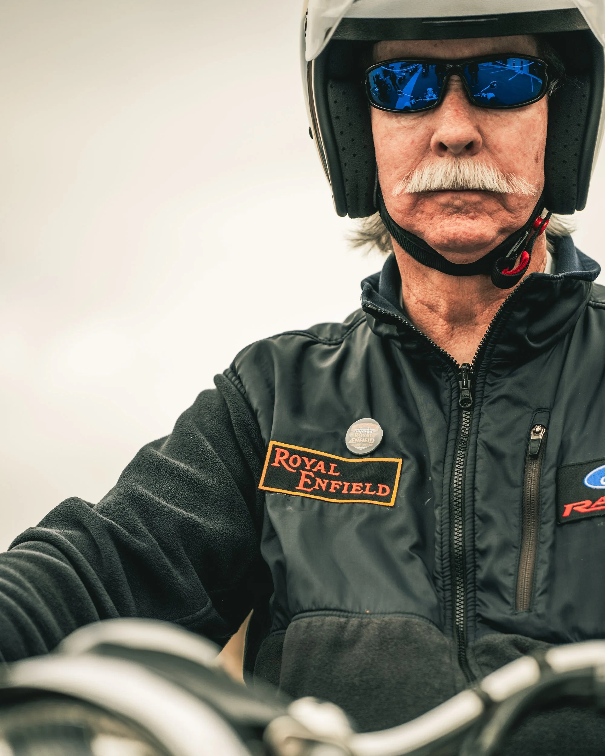 Portrait of an older rider in a helmet and Royal Enfield jacket at One Ride 2026