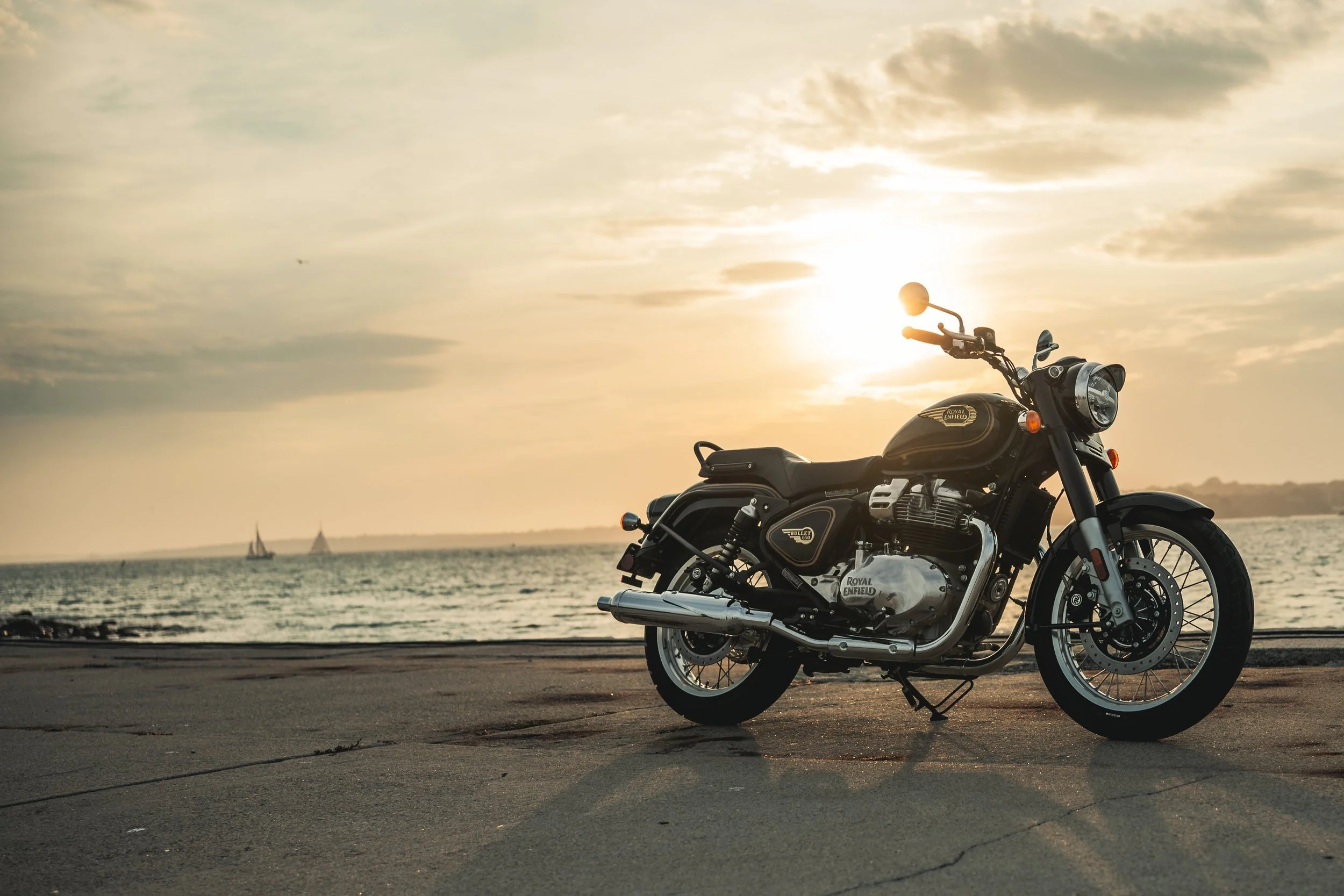 Royal Enfield Bullet 650 silhouetted against a sunset over the ocean