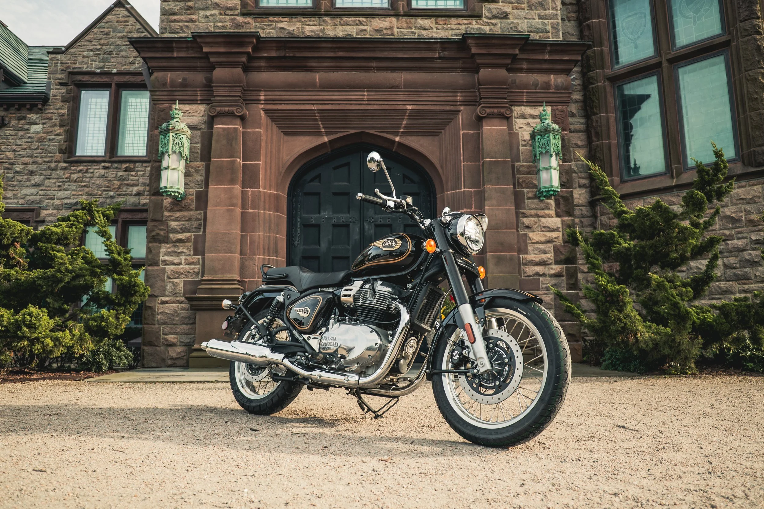 Royal Enfield Bullet 650 parked by a stone mansion entrance at Audrain