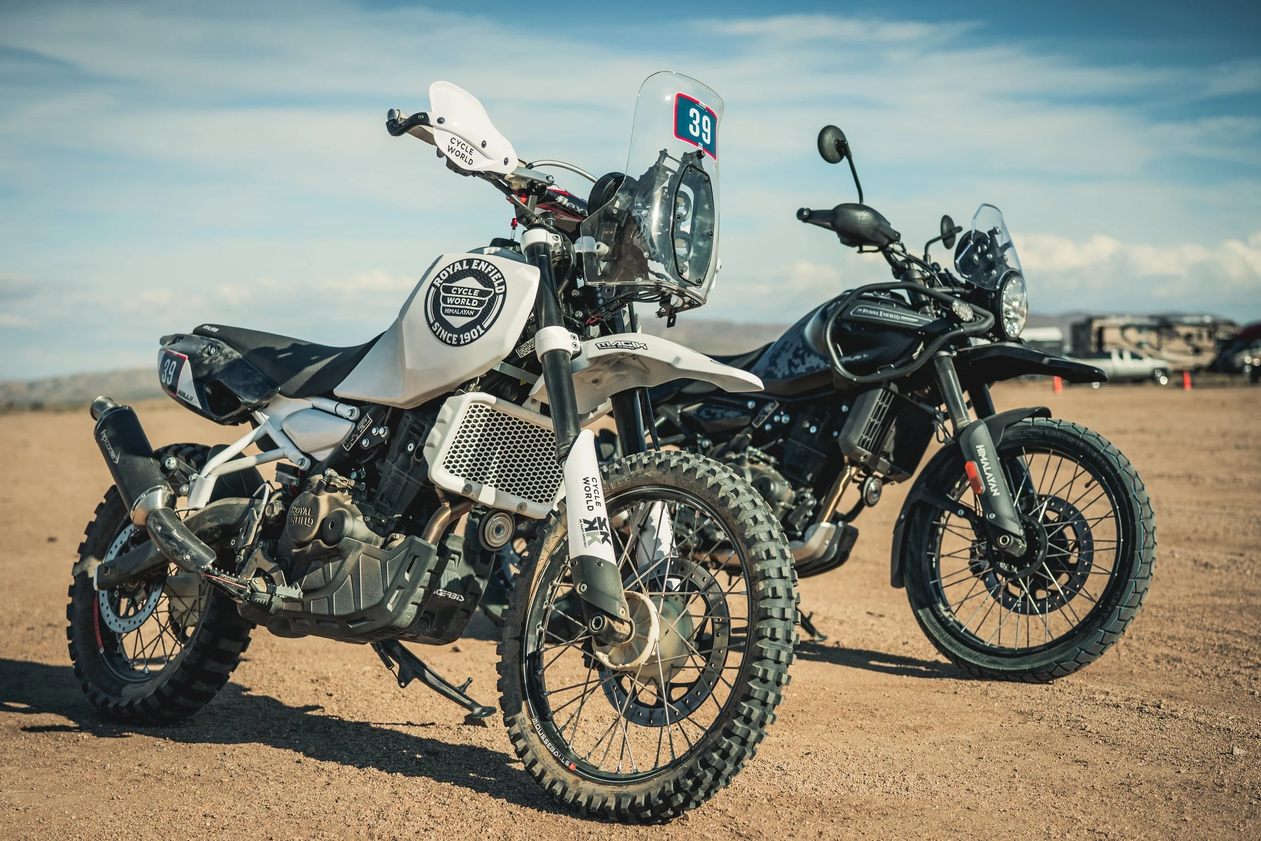 Two Royal Enfield adventure motorcycles on a dirt lot for Cycle World