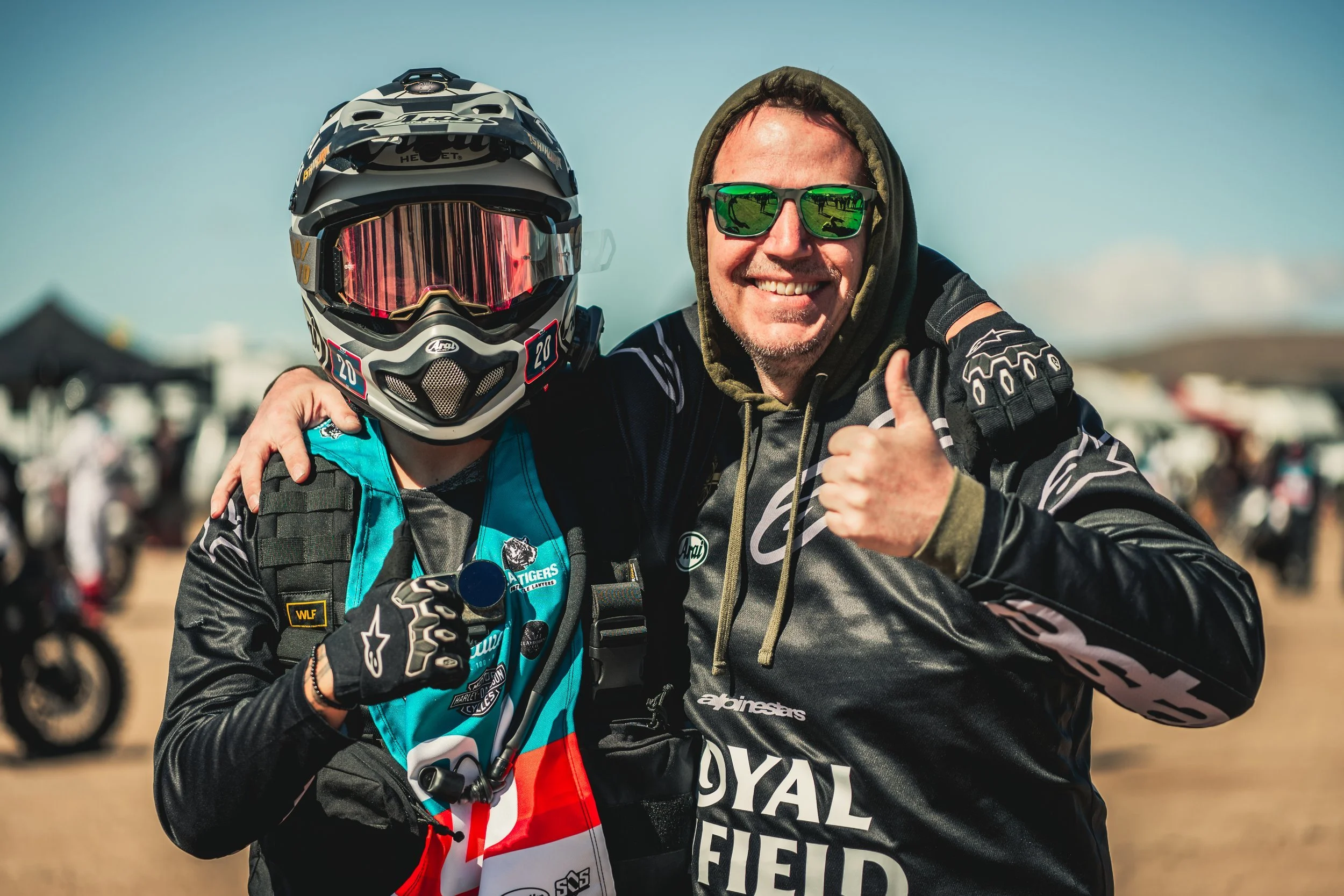 Two Royal Enfield racers smiling in helmets at the Biltwell 100