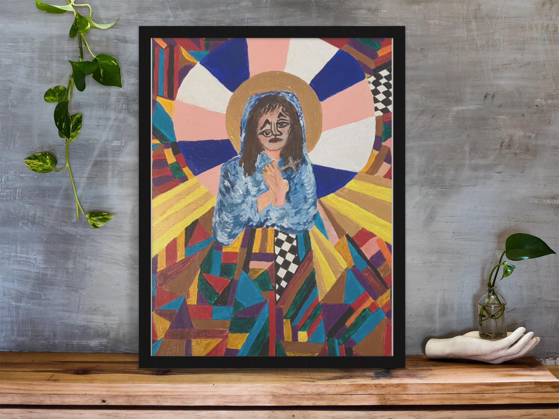 framed-art-print-standing-on-a-wooden-desk-against-a-concrete-wall-near-a-hand-decoration-a10403.png