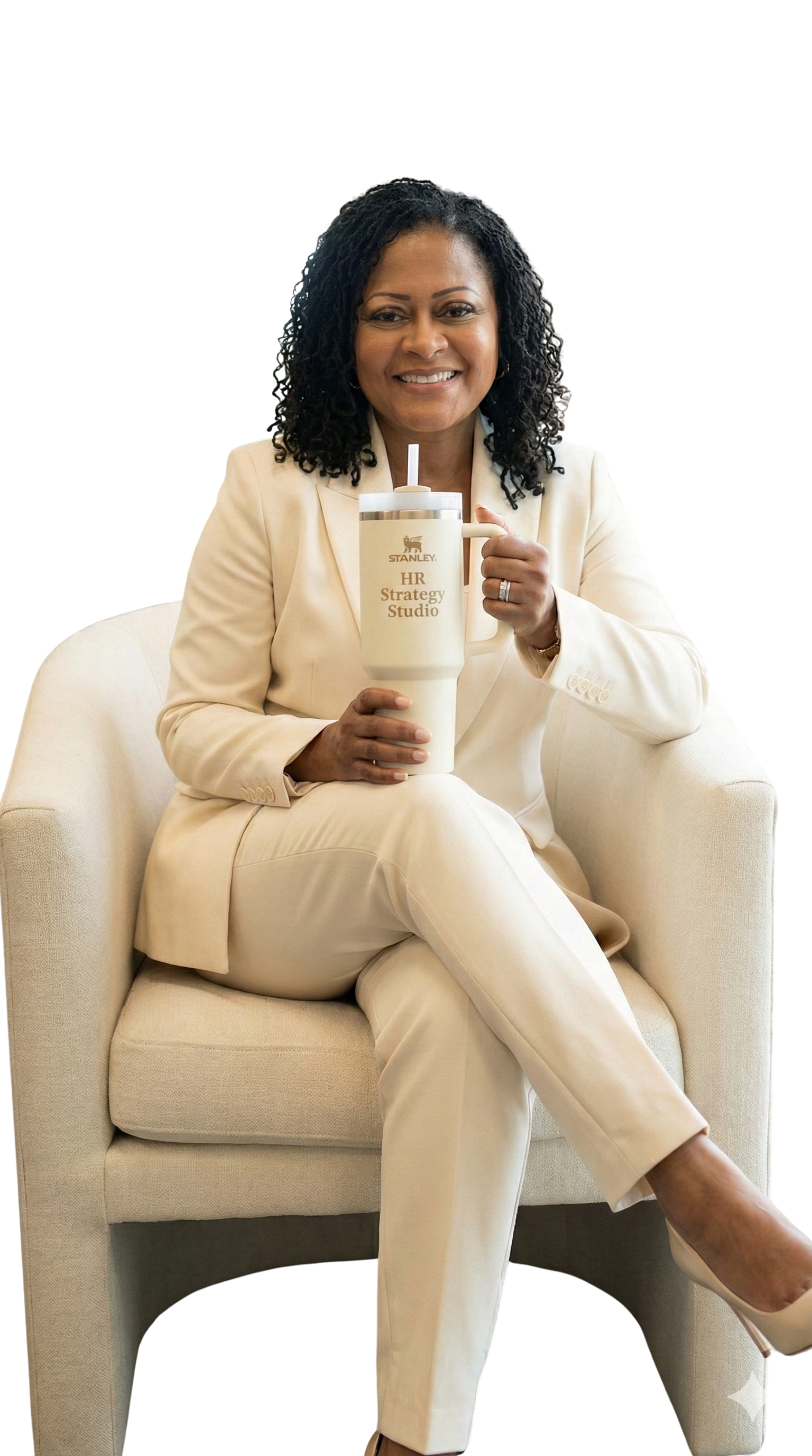 Woman sitting in cream chair wearing a cream professional suit with her leg crossed, holding a cream stanley cup with  HR Strategy Studio on it in gold font.