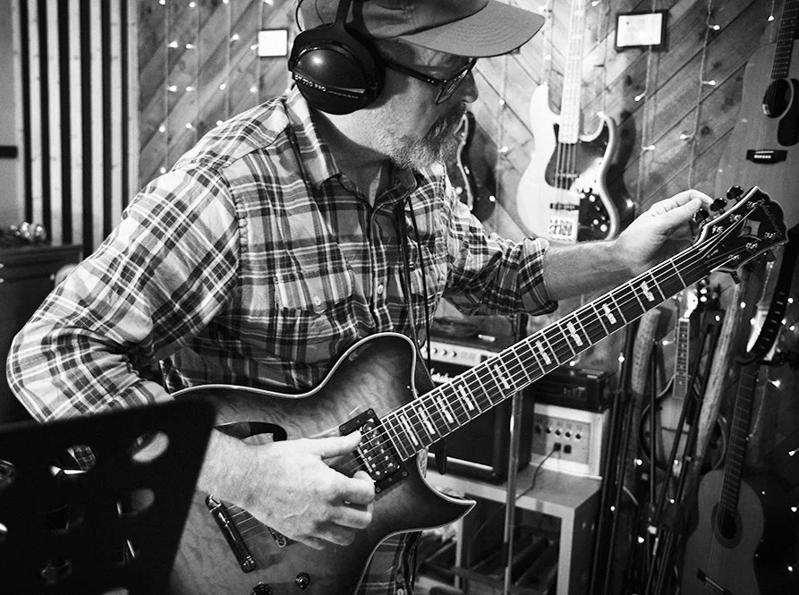 Greg in the studio tuning a guitar and getting ready to play