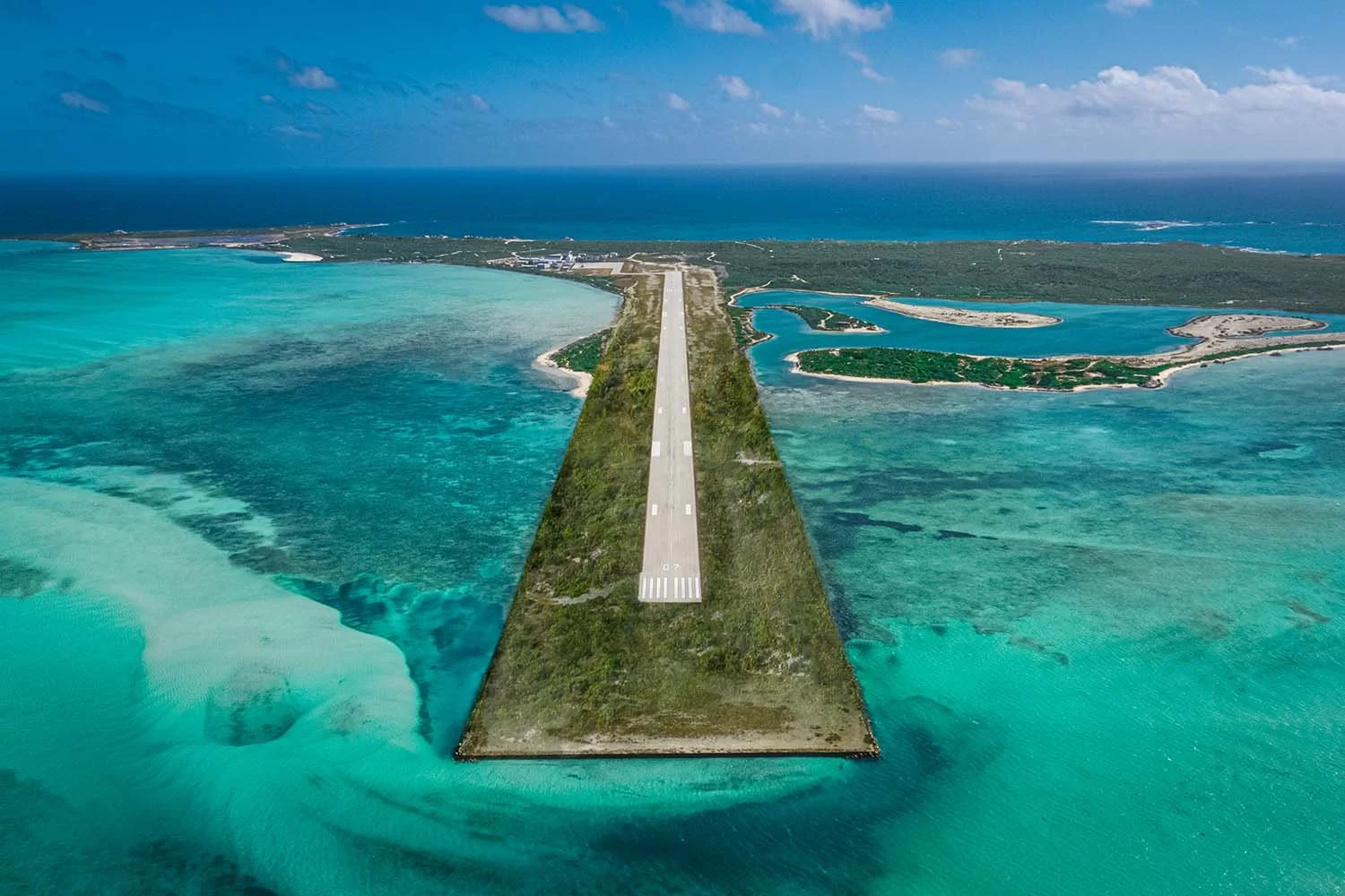 Aerial view of the private runway at Ambergris Cay, a private island resort in Turks and Caicos, surrounded by turquoise shallows and coral reef
