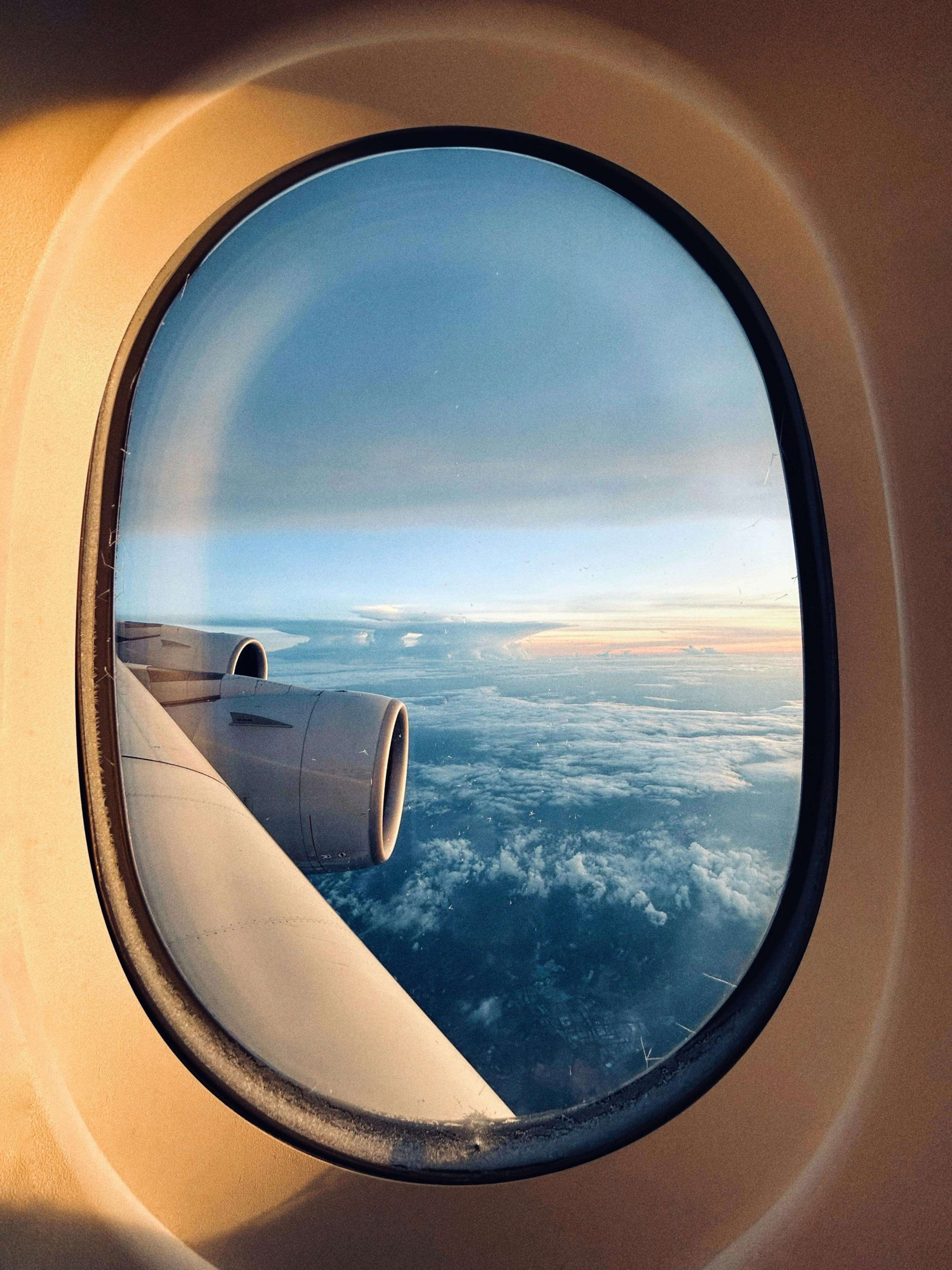 View of clouds and sky from an airplane window with the airplane's engine visible.