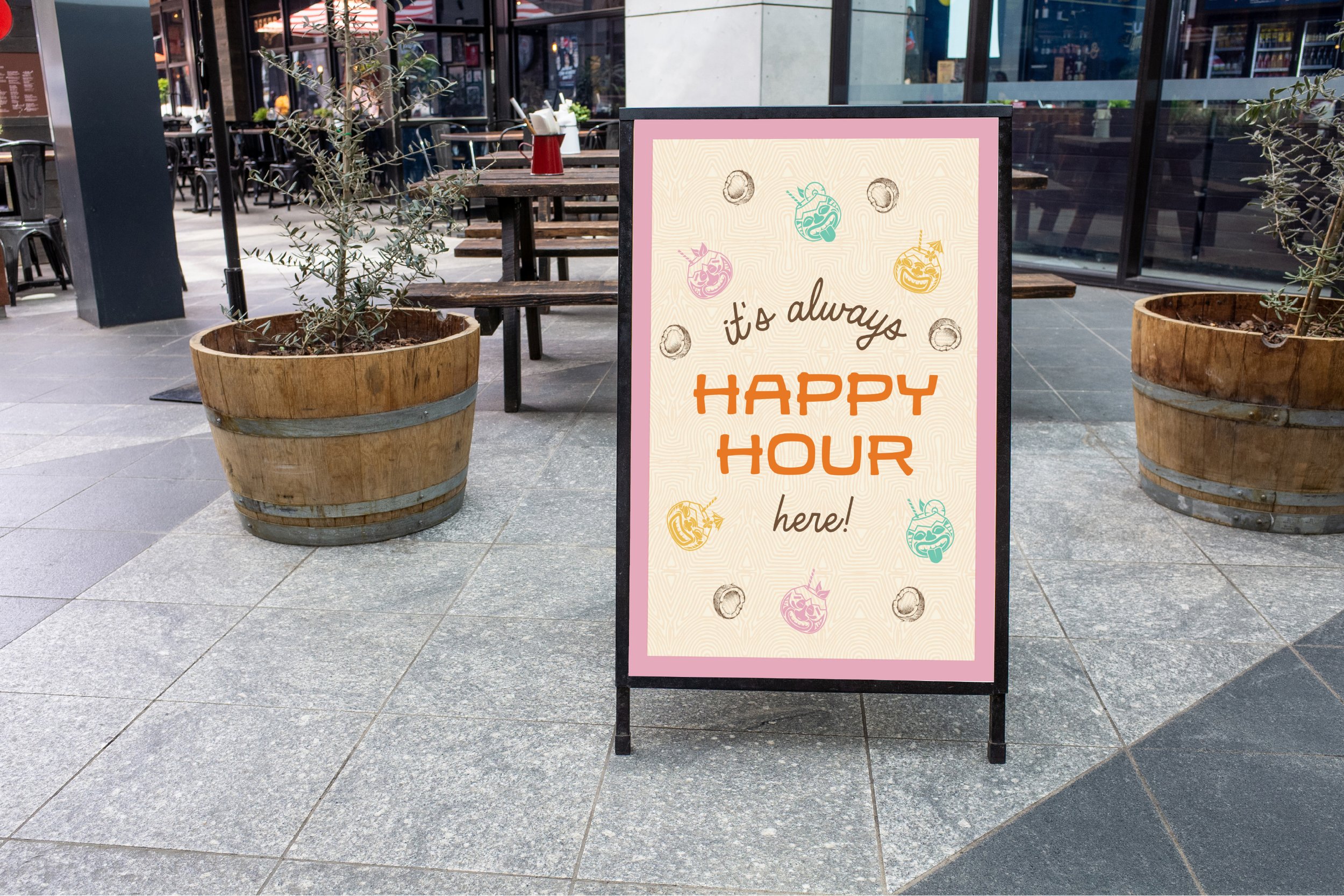 A sidewalk sign advertising happy hour at The Broken Coconut, surrounded by large wooden planters with plants, located outside in an urban setting.