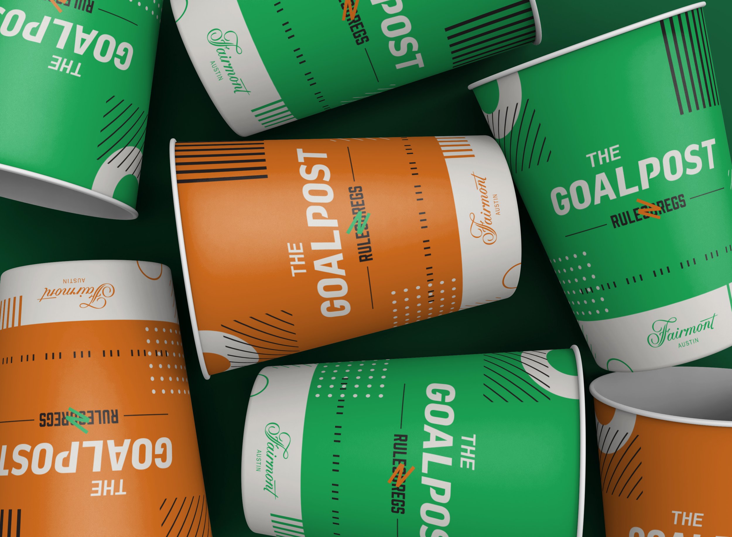 Multiple cups with colorful designs featuring the phrases 'The Goalpost' and 'Rules of Reggs,' in green, orange, and white, on a dark green surface.