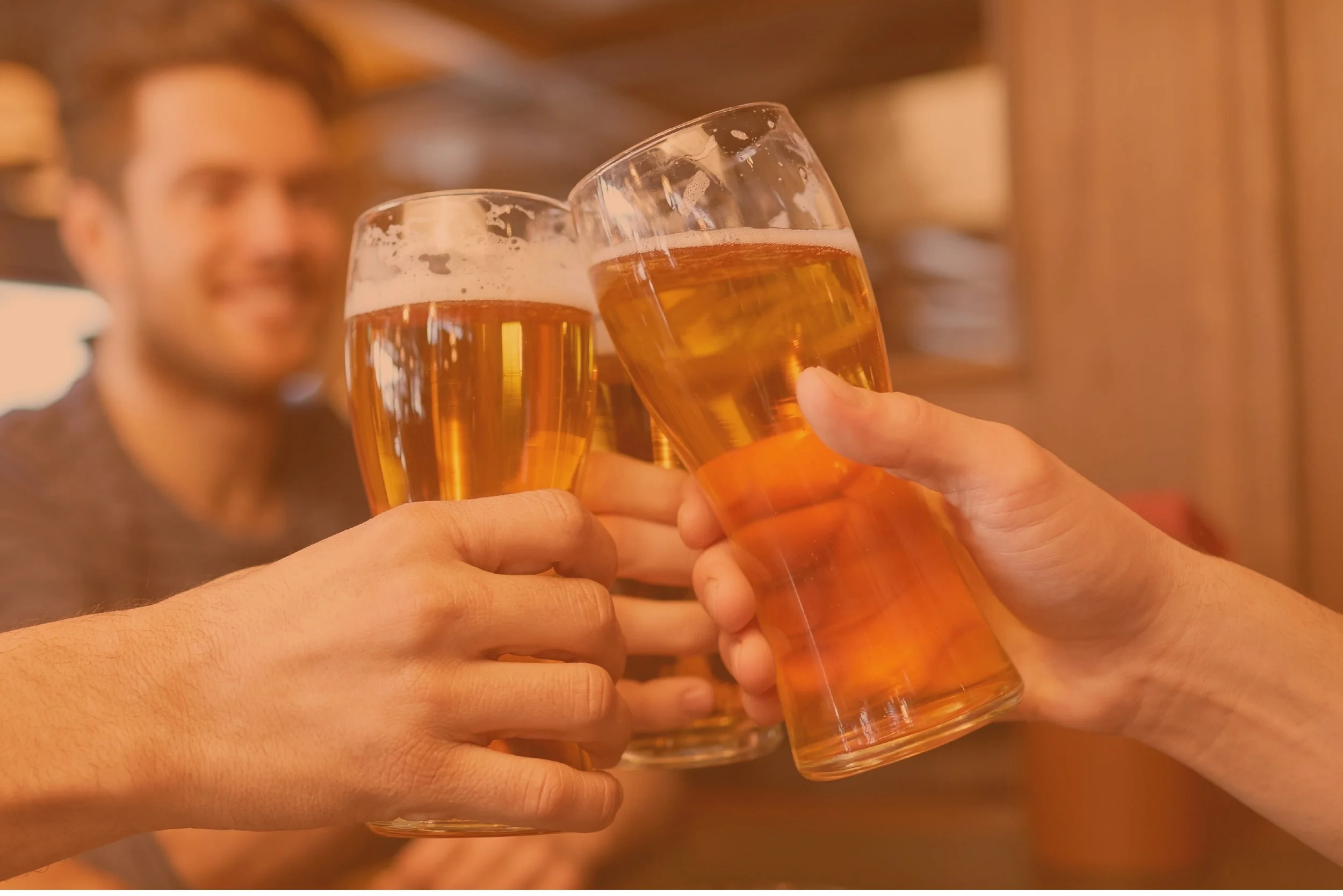 People celebrating with clinking glasses of beer in a bar or restaurant.