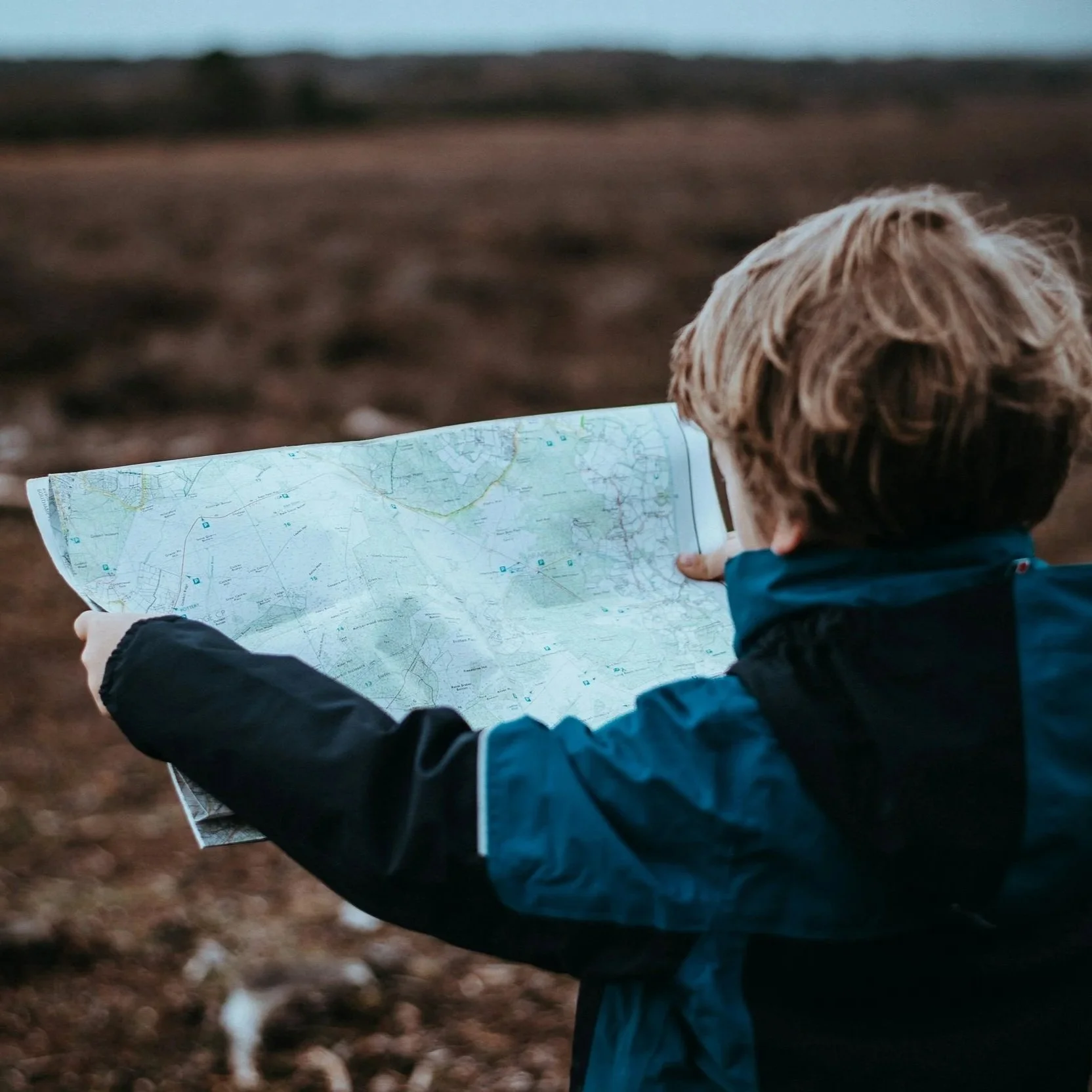 Child holding a large road map outdoors