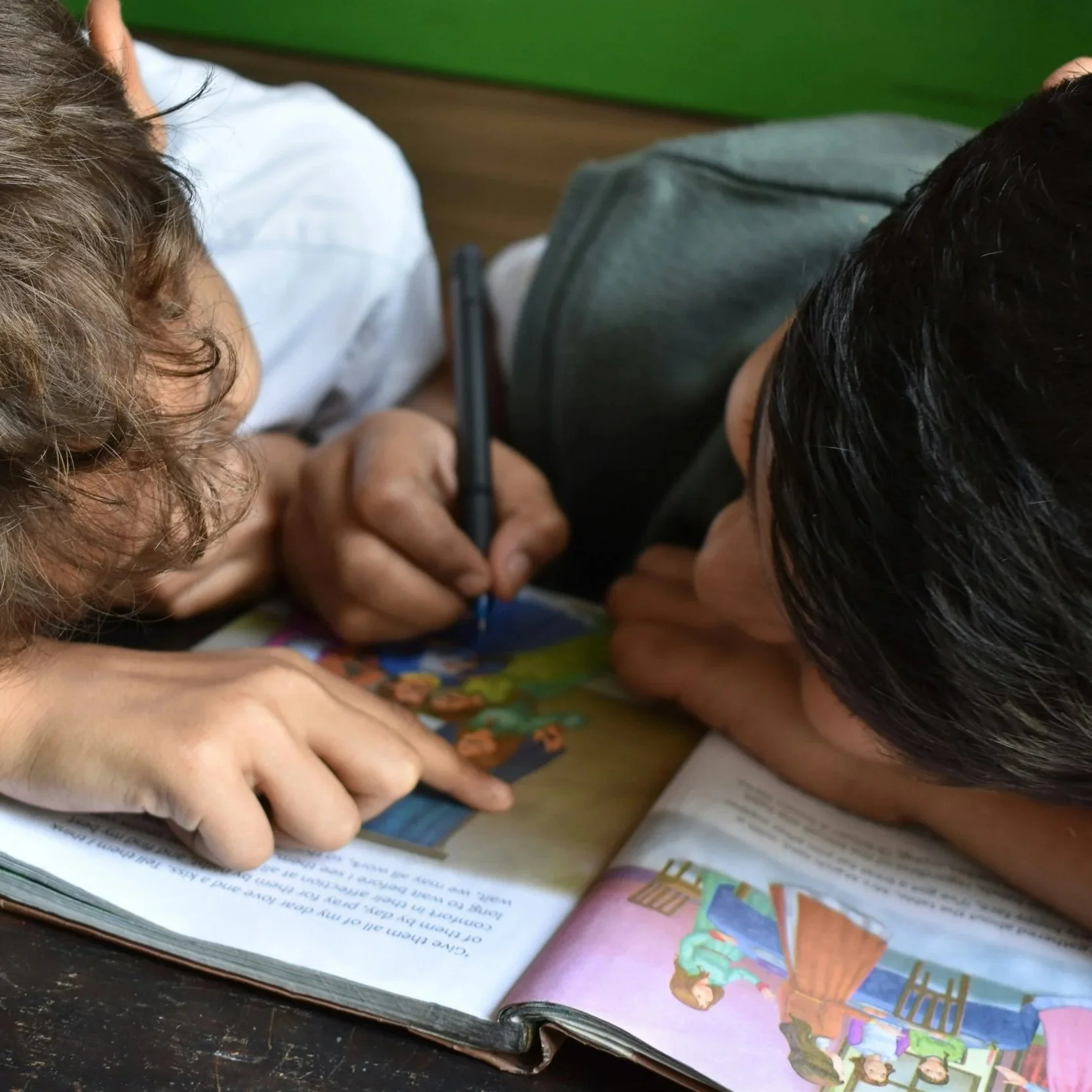 Two young children reading and writing together