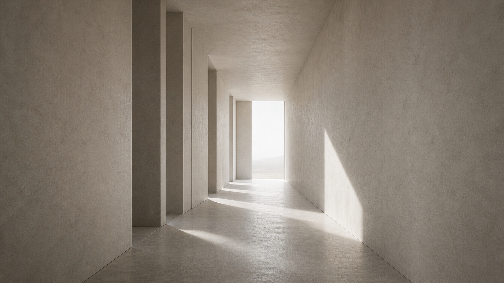 Long, minimal corridor with pale walls and floor, leading toward a bright open space at the far end.