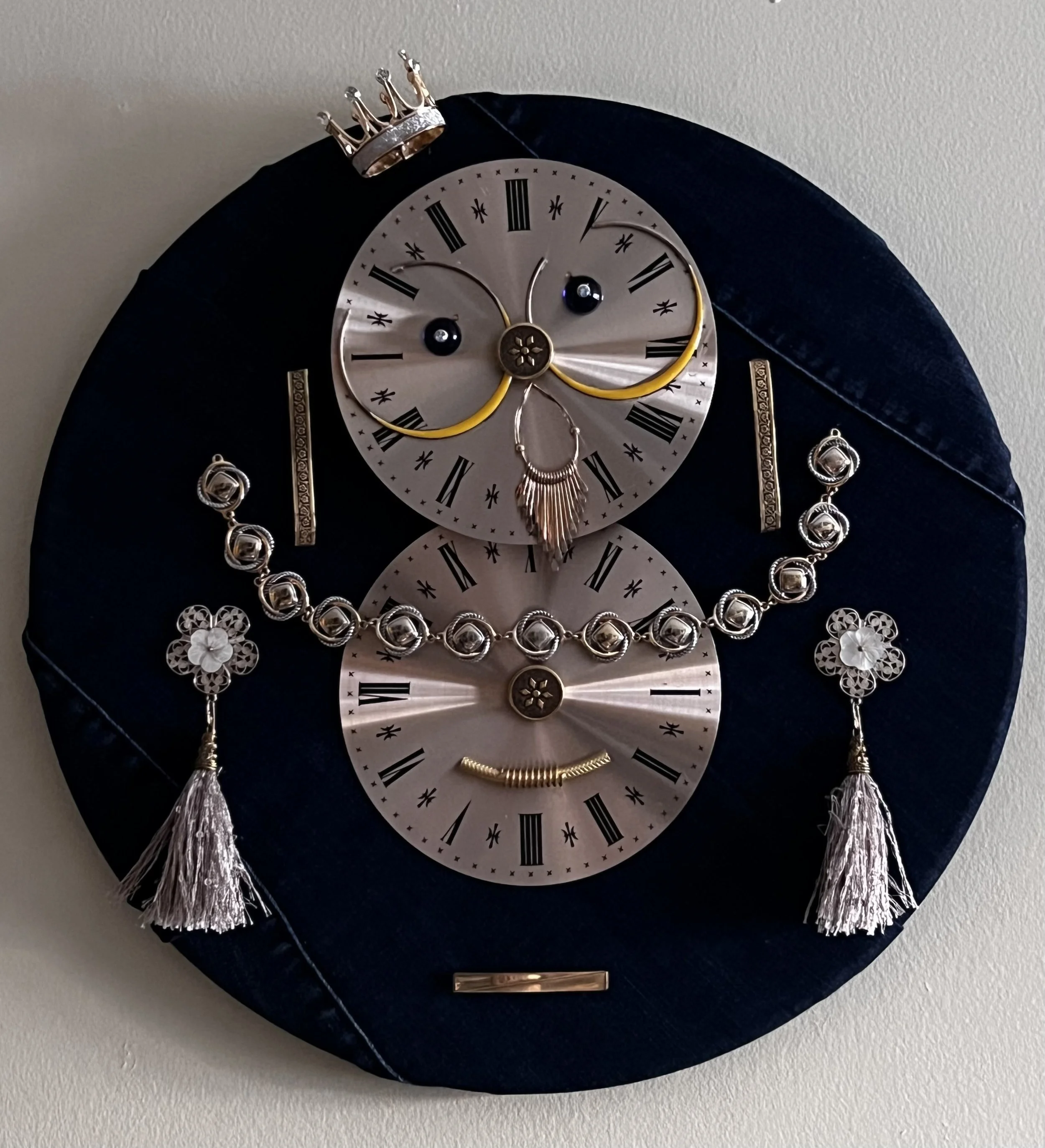 A decorative wall clock with a black oval background, adorned with jewelry including a necklace with round silver beads, earrings with tassels, and a hairpin, arranged on the clock face.