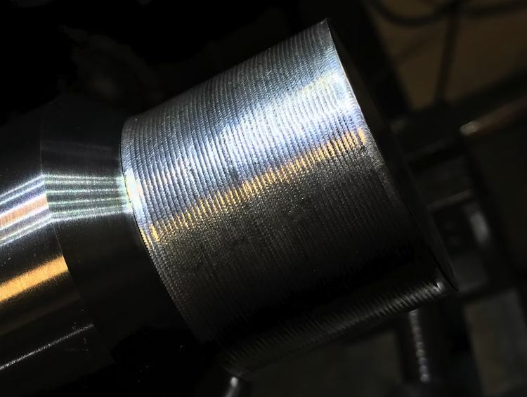 Close-up of a cylindrical metal object with a textured surface and smooth, shiny ends, possibly a machined part.