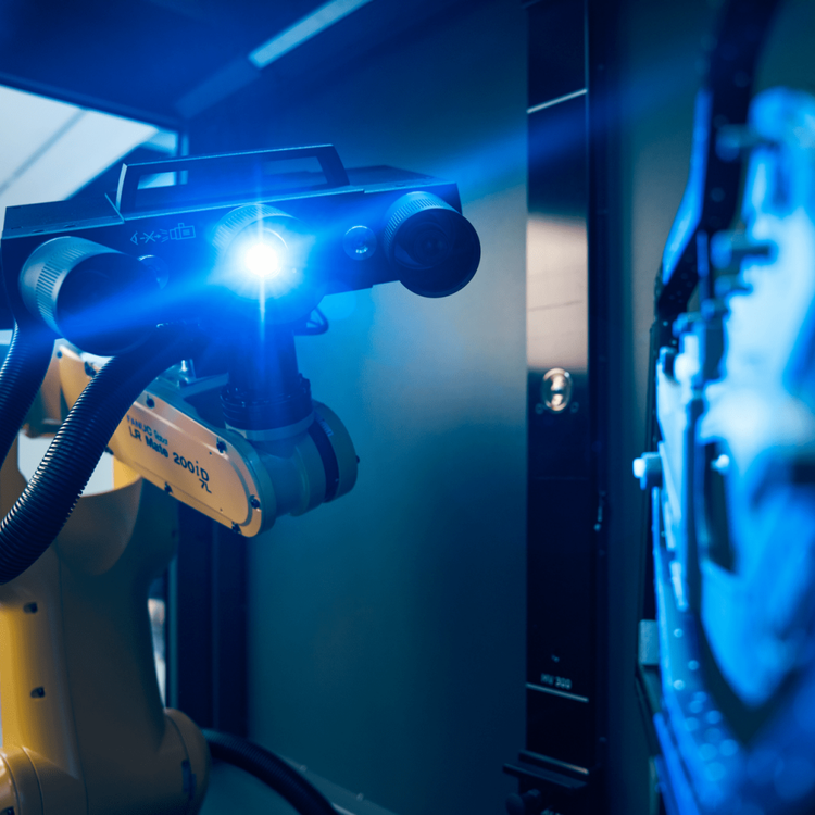 A robotic surgical device equipped with a camera, emitting a blue light, in a high-tech medical or laboratory setting.