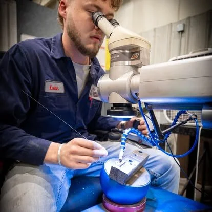 A scientist looking through a microscope in a laboratory setting.