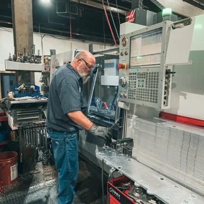 Man operating a large industrial CNC machine in a workshop.