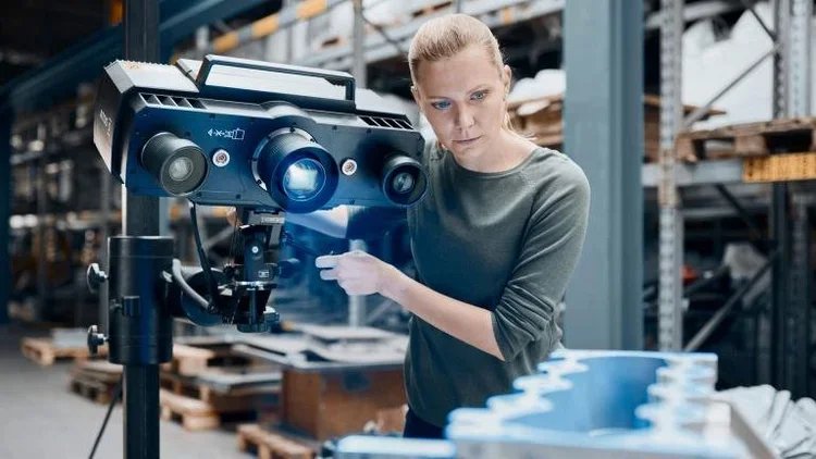 A woman inspecting a large industrial machine in a warehouse.