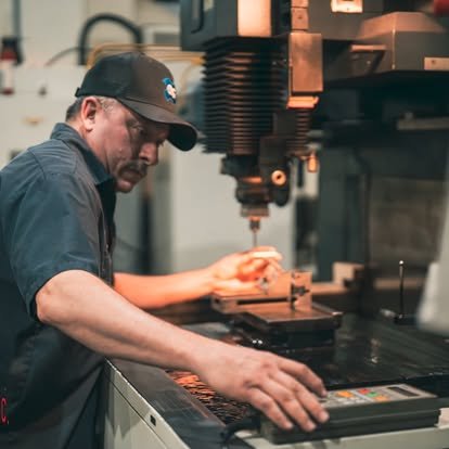 A man operating a CNC milling machine in a workshop