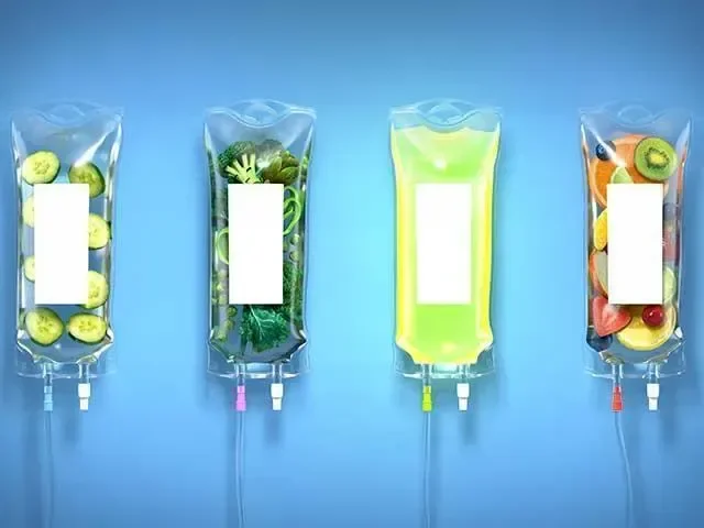 Four IV bags filled with different liquids and fruits, including cucumbers, broccoli, and mixed fruits, against a blue background.