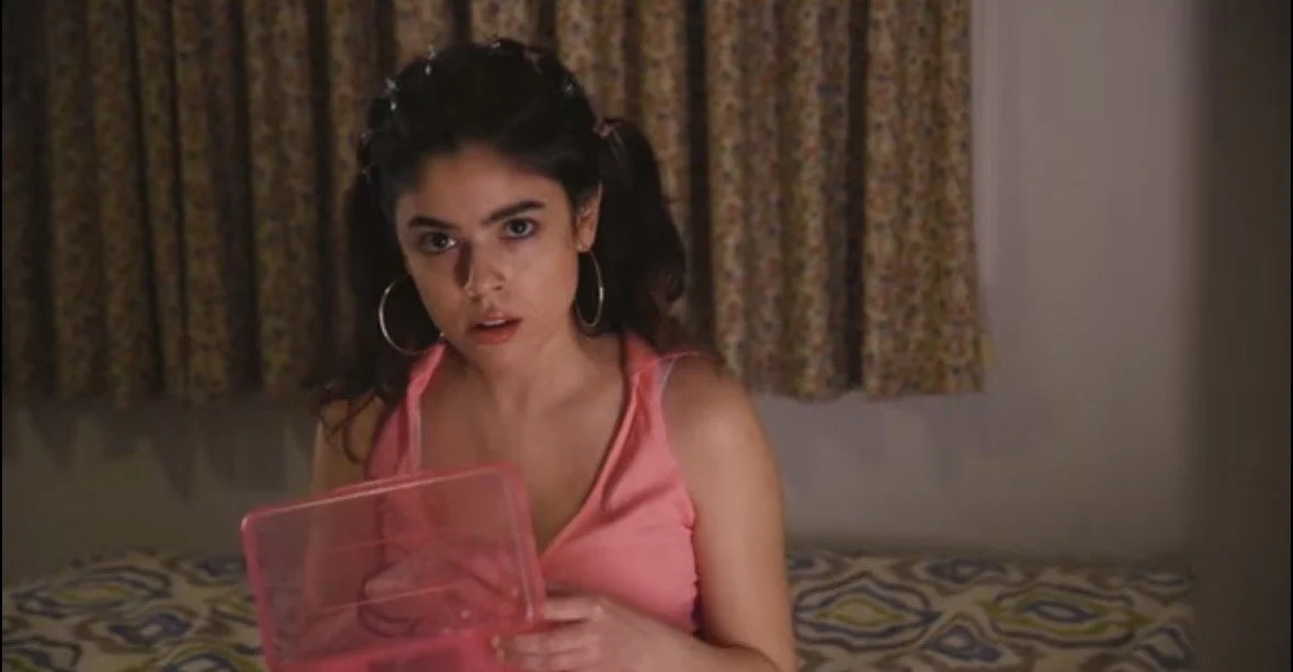 Close-up of a young female actress with dark brown hair, brown eyes, and light skin, wearing a pink halter top, big hoop silver earrings and 90s inspired butterfly clips. Film and tv actress. Documentary. Silence on the Streets. 
