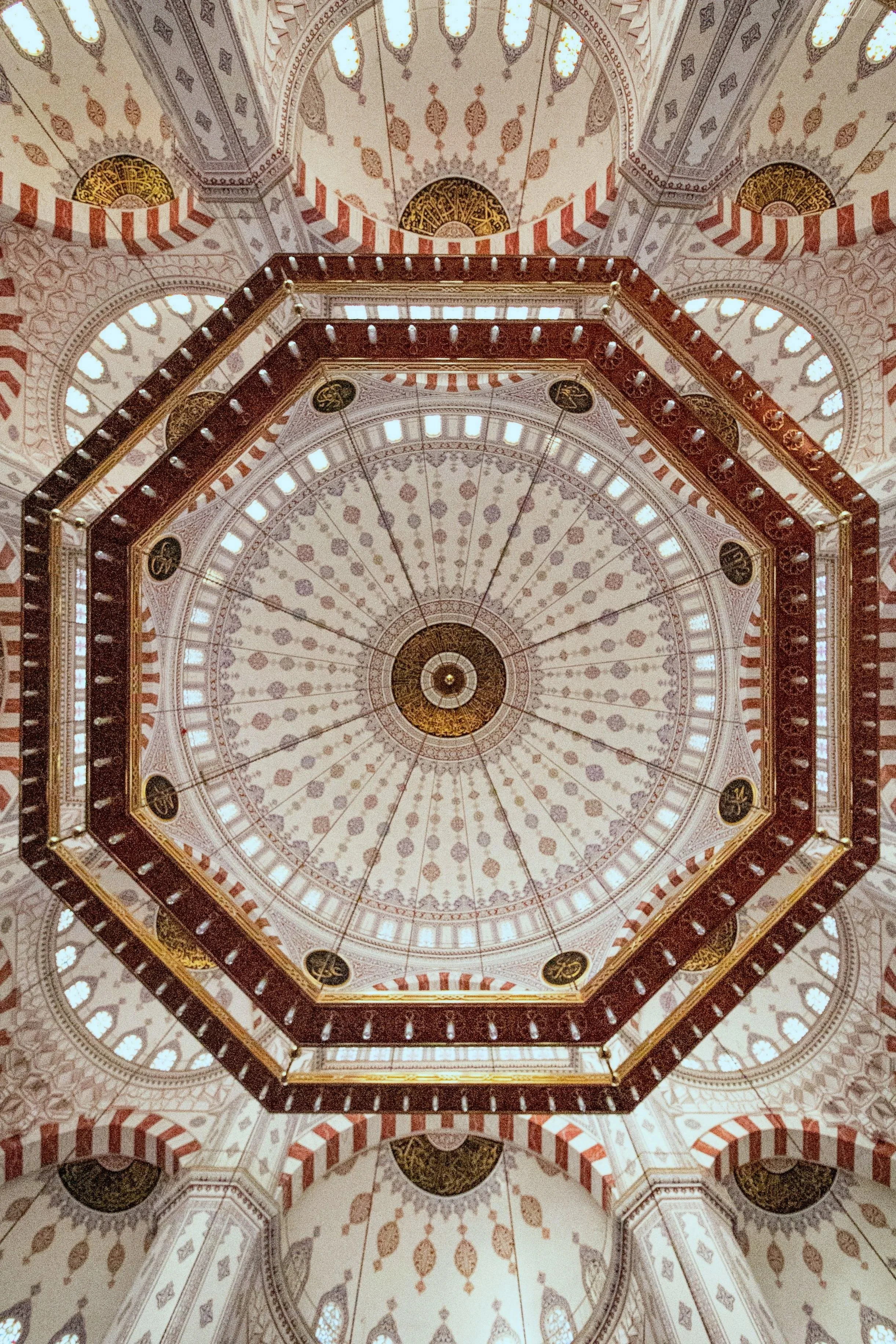 Interior view of a decorated dome ceiling with intricate patterns, arches, and windows.