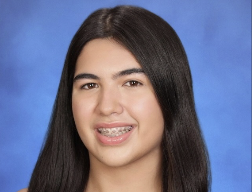 A young woman with long dark hair, smiling against a blue background.