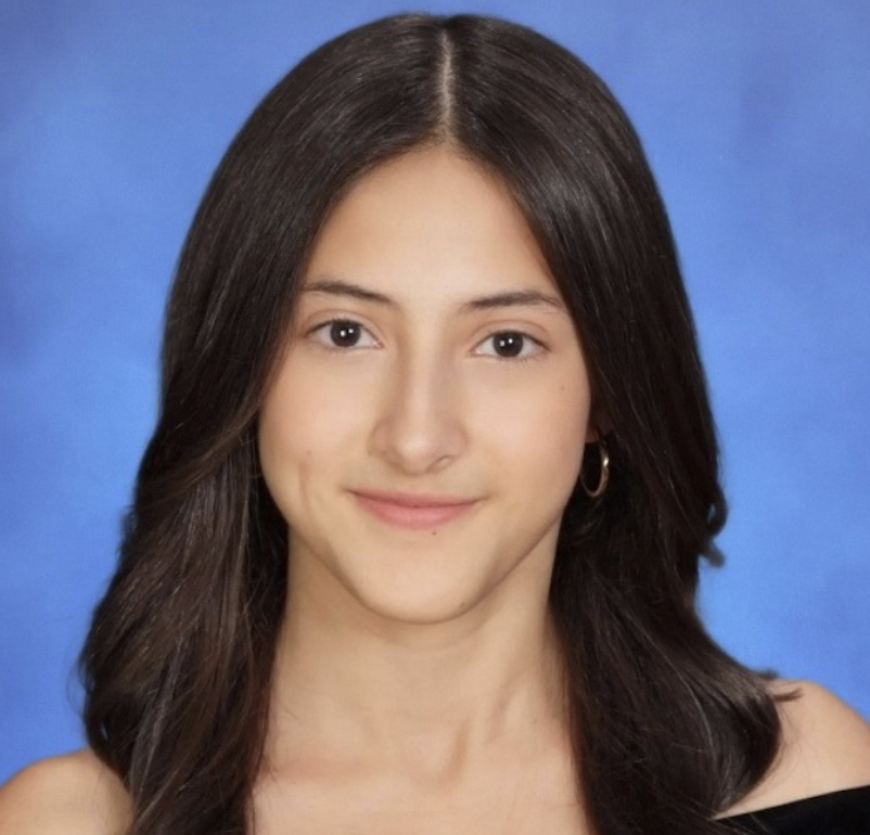 Young woman with long dark hair, wearing small hoop earrings, smiling, against a blue background.