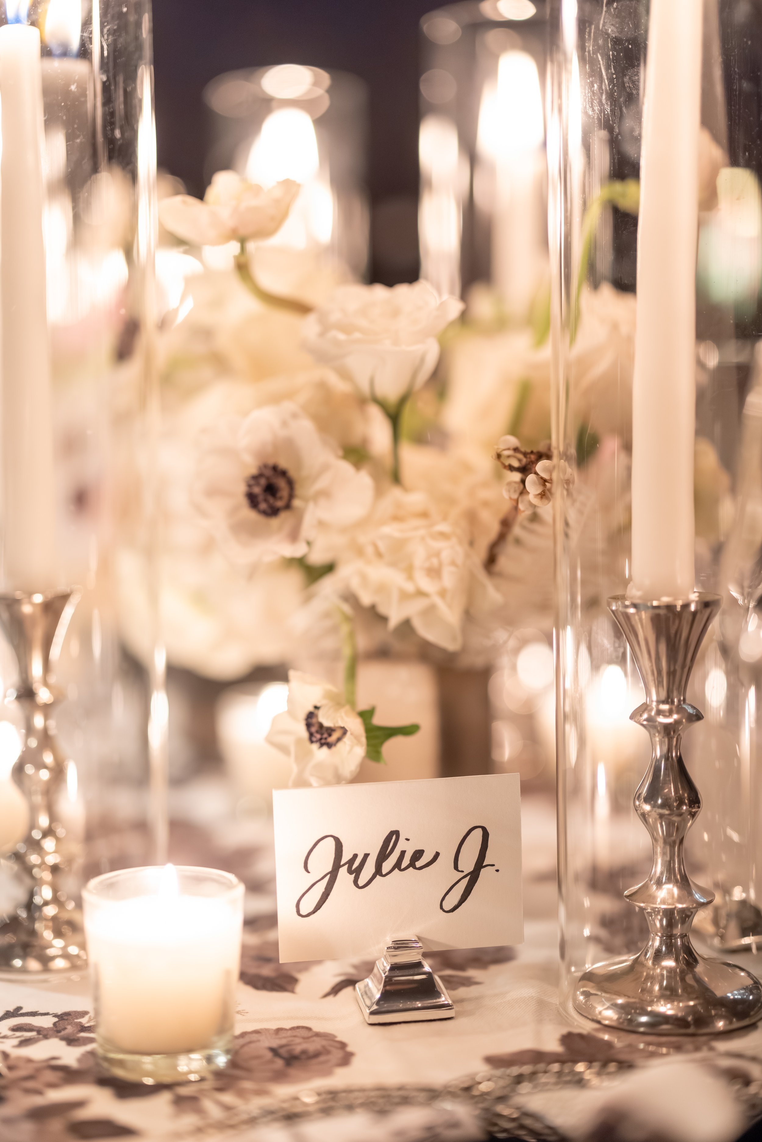 Elegant table setting with white flowers, candles, and a name card reading 'Julie J.'