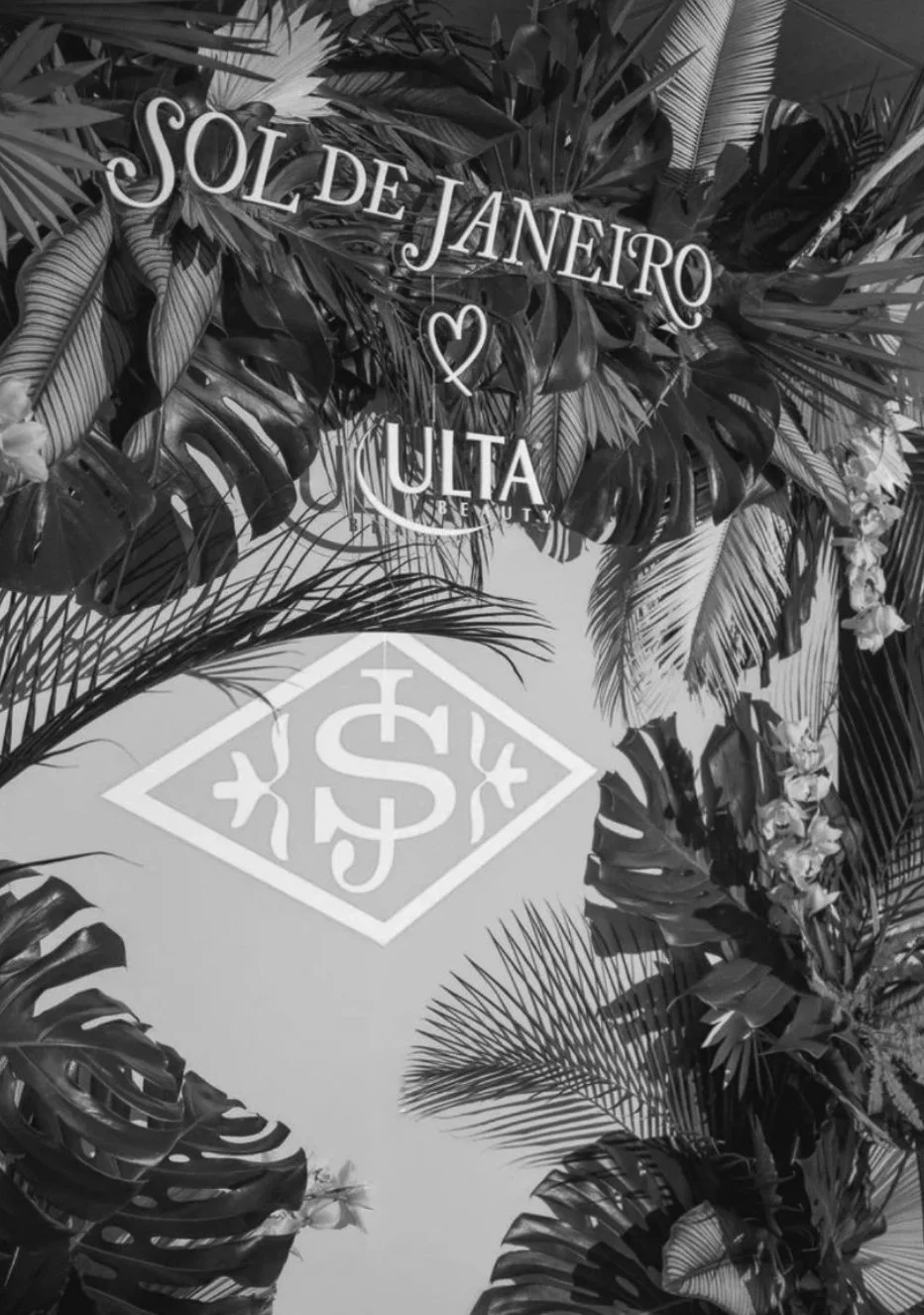 Decorative backdrop with tropical leaves and flowers featuring the text 'Sol de Janeiro' and the Ulta Beauty logo at the center.