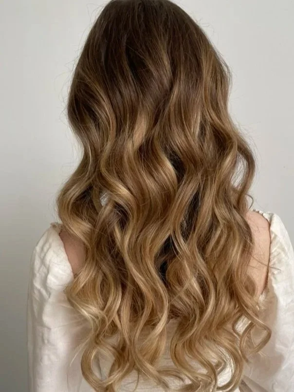 Back view of a woman with long, wavy, light brown hair.