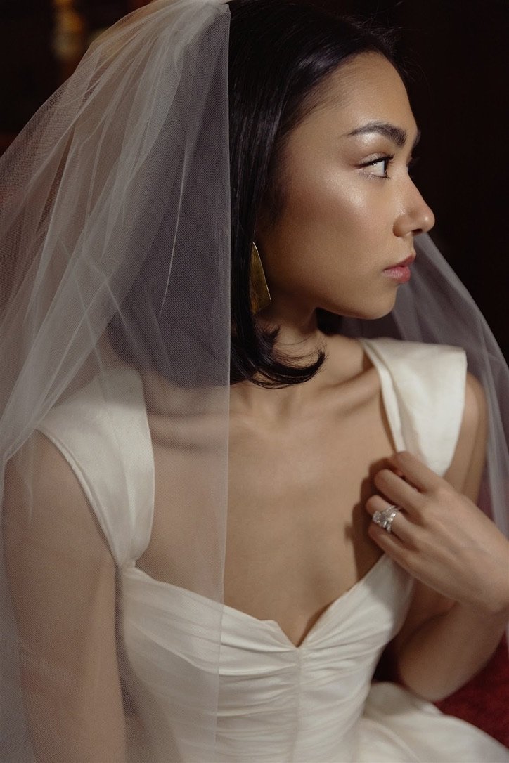 A woman in a wedding dress with a veil looking to the side in a profile view.