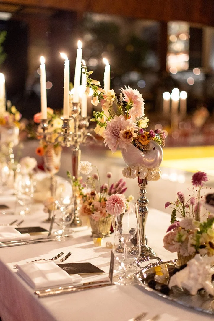 Elegant table setting with floral centerpieces, lit candles, and silverware.