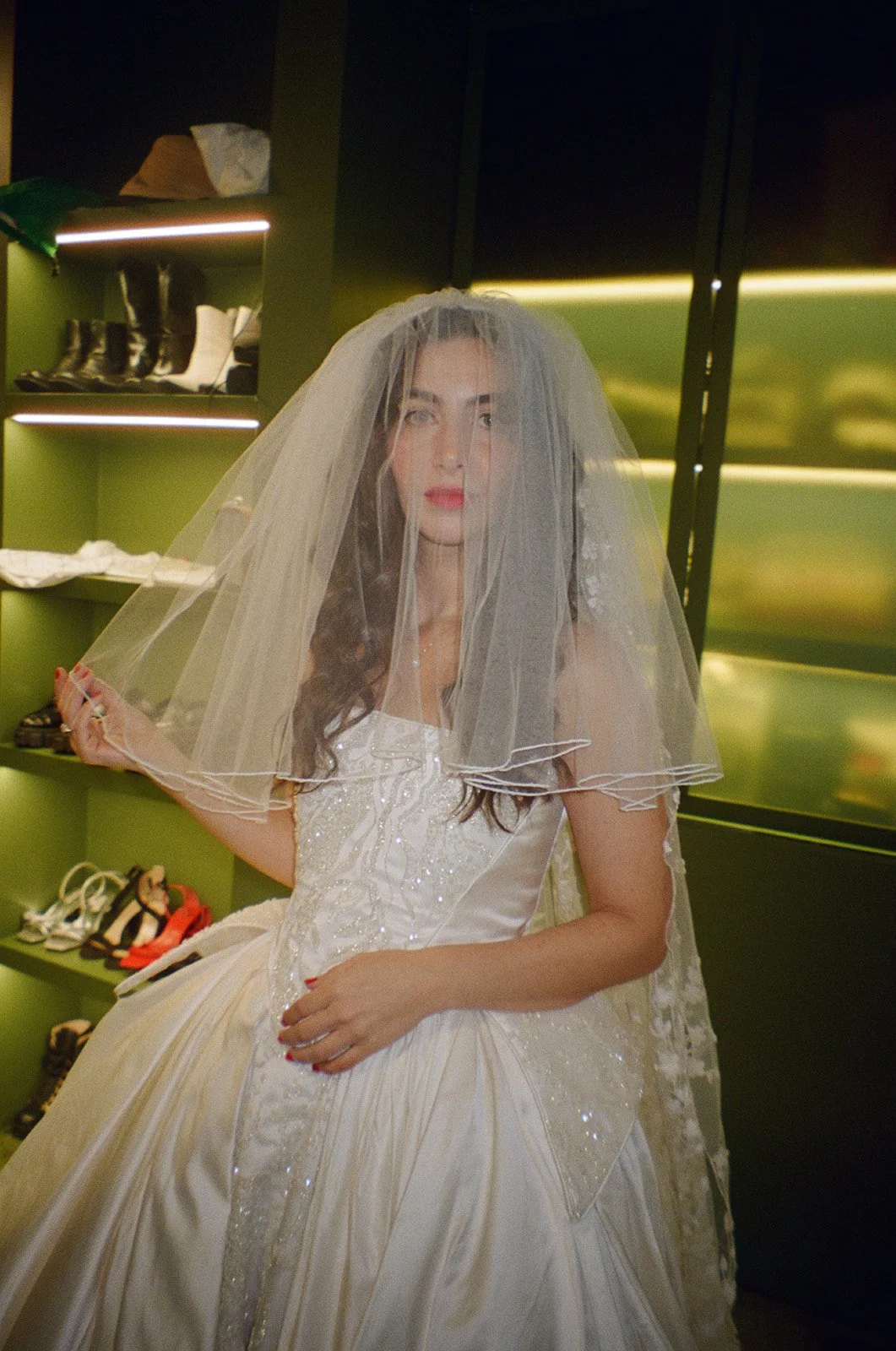 Woman trying on a wedding dress and veil in a shoe store.