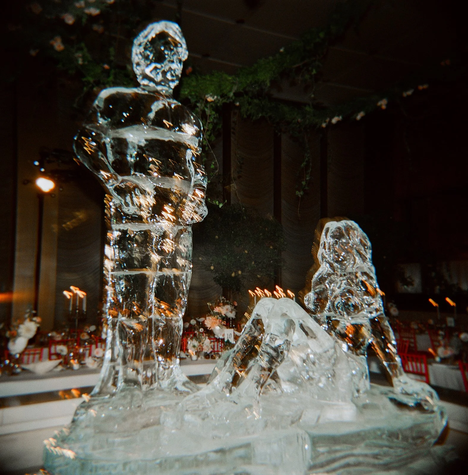 Ice sculpture of a man and dog at a decorated event venue.